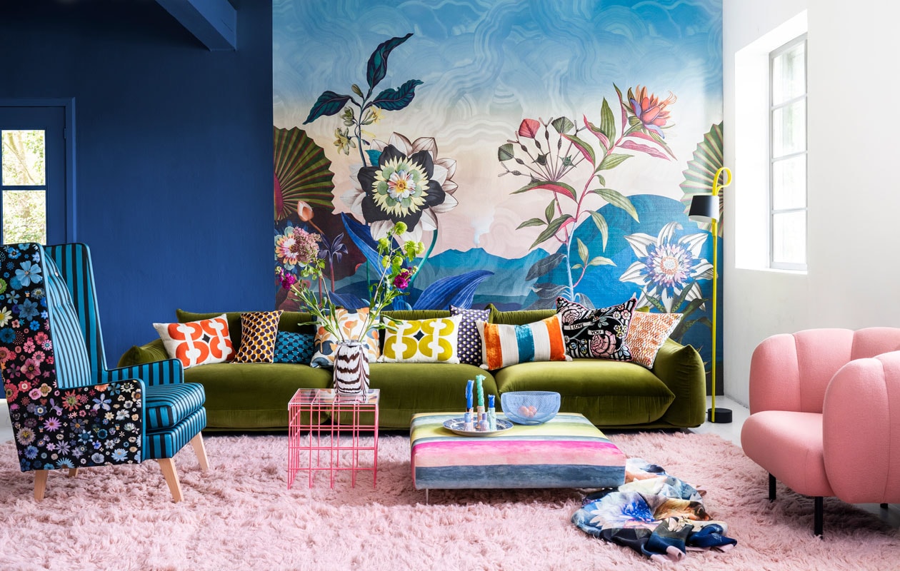 Paneel met behang Atlantis Aube van Christian Lacroix voor Designers Guild, 300×350 cm € 927,- (wva.nl). Blauwe muurverf Exciting Night No. 96 van Lab Paint, per liter € 45,- (vestingh.nl). Groene velours bank van Arflex, 96x354x70 cm (dxbxh) € 5709,-, roze fauteuil van Warm Nordic, 95x84x80 cm (lxbxh) € 2190,-, zachtroze hoogpolig wollen vloerkleed van Layered, 250×350 cm € 1090,- (goeds.nl). Multikleurige voetstoel in stof Rayure Chinoise Alchemilla van Designers Guild, 90×90 cm € 1485,-, oorfauteuil Harper Chair bekleed met stoffen van Christian Lacroix voor Designers Guild € 3220,- (wva.nl). Verstelbare vloerlamp € 659,- (hay.nl). Roze staaldraad tafel van Bold Monkey, 41x41x40 cm (lxbxh) € 165,- (boldmonkey.com). Kandelaars vanaf € 14,50, kaarsen van Hay, per 6 € 25,- (vtwonen.be). Glazen vaas € 85,- (hay.nl). Vintage bord € 25,- (hetgroteavontuur.nl). Blauwe gaasschaal € 39,- (festamsterdam.com). Kussens van links naar rechts: rood geborduurd € 149,-, langwerpig model van zijde, per stuk € 89,- met bloemdessin € 109,-, groen geborduurd € 149,-, alles van Lelievre (loggerewilpower.com), velours streep van William Yeoward € 121,-, bloemen Christian Lacroix voor Designers Guild € 192,-, geborduurd € 132,-, wollen plaid van Designers Guild € 327,- (wva.nl). vtwonen 06-2022 | styling Marianne Luning | fotografie Stan Koolen