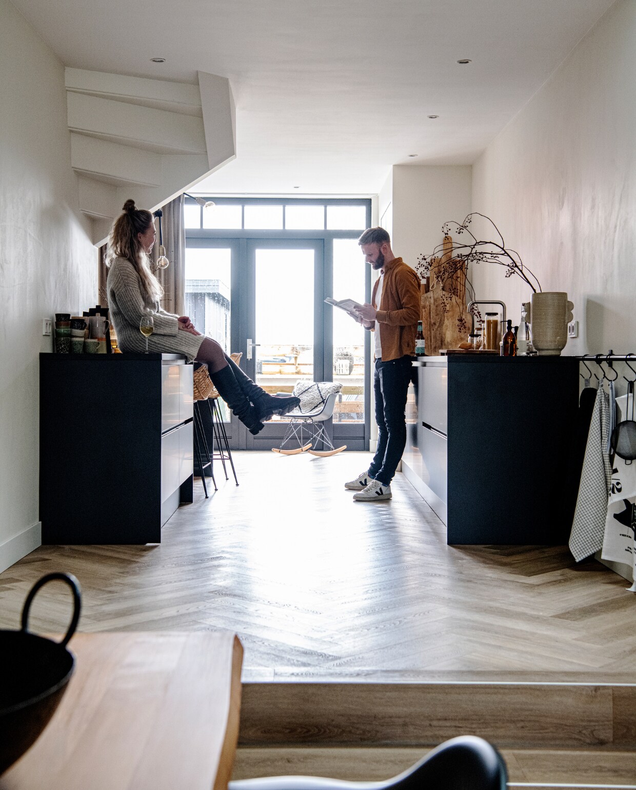 Muurverf RAL 9010. Vloer naturel eiken visgraat pvc. Keuken Keuken Kampioen. Barstoelen MeubelAsia. Mokken en kan HKliving. Eames-schommelstoel Vitra. Kussen in stoel HKliving. Houten planken Pluk, Xenos en Loods 5. Voorraadpotten Loods 5, zeeppompjes Wellmark. Vaas Urban Nature Culture. Steigerbuis Karwei, haken Dille &amp; Kamille. Theedoeken Dille &amp; Kamille en Elias. Overig onbekend. vtwonen 12-2022 | Productie InsideHomePage | Styling Studio Marit Saladini | Fotografie Louis Lemaire | Tekst Saskia Borst