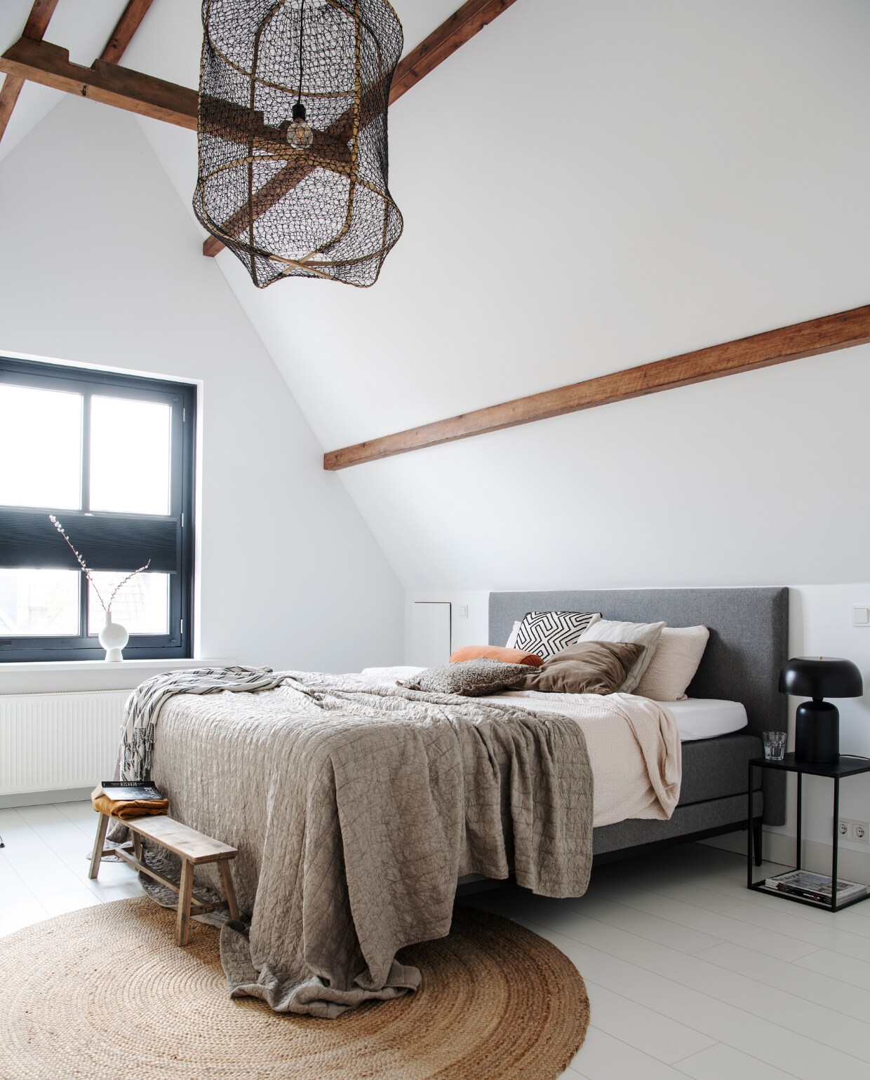 Muurverf Stralend Wit van Flexa. Wit laminaat Kwantum. Vaas Madam Stoltz. Bed Swiss Sense. Dekbedovertrek, zwart-wit kussen en fluffy kussen Loods 5. Oranje kussen Hinck, bruin kussen Madam Stoltz, sprei Jysk, zwart-witte doek H&amp;M Home. Houten bank Xenos. Vloerkleed Praxis. Nachtkastje Loods 5. Zwarte lamp Loods 5. Overig onbekend. vtwonen 12-2022 | productie InsideHomePage | styling Studio Marit Saladini | fotografie Louis Lemaire