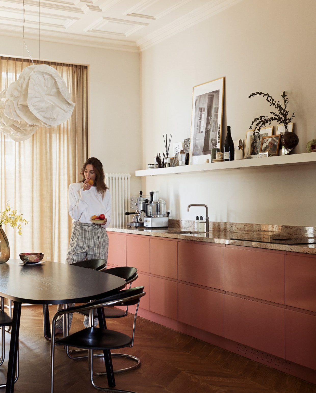Rechte keuken zonder keukenkastjes, Houten vloer gelegd in Hongaarse punt laminaatenparket.nl. Stoelen en gordijnen Marktplaats. Eettafel Studio Henk. Hanglamp Belux Cloud van Frank Gehry. Keuken basis van Ikea, fronten Frontz. Granieten aanrechtblad De Keukenbladen Fabriek. Kookplaat Bora. Kraan Quooker. Keukenmachine Magimix. Koffiezetapparaat Isomac. Geurstokjes Marie-Stella-Maris. Cocktailshaker erfstuk van Lidians grootouders. Servies van Louks grootouders. Madeleinevorm en Droste chocoladevorm antiekmarkt. Verfkleur achterwand Ral 9001. Verf plafond Ral 9010. Overig onbekend. vtwonen BK8- 5 2022 | styling Ilona Jongepier |  fotografie Dana van Leeuwen | tekst Jana Voyvodich