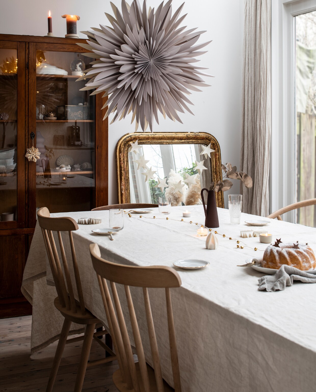 Eettafel: schragen Hay, blad Pontmeyer, zelf geschilderd en bevestigd. Stoelen Dille &amp; Kamille. Tafelkleed en kandelaars H&amp;M Home. Kan Cube White Conceptstore, glas met gouden rand Hay, kristallen glazen erfstuk. Kerstdecoratie Sissy-Boy, spiegel Frans vintage, sterrenslinger zelfgemaakt. Kast Marktplaats. NEE | vtwonen 13-2022 | productie Insidehomepage | styling Myla Griese | fotografie Louis Lemaire | tekst Inge van Lieshout