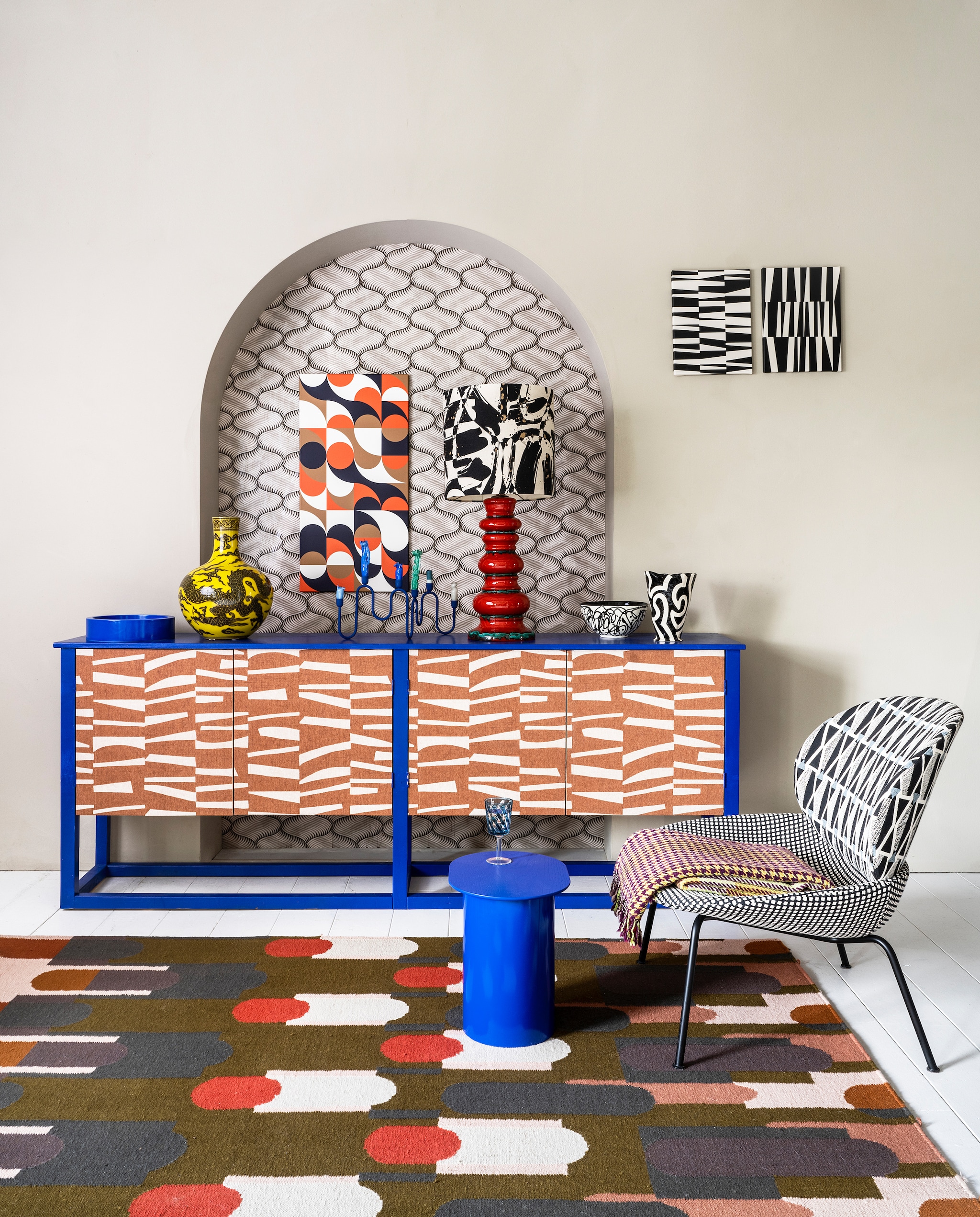 In de nis met de hand bedrukt behang Cheveux d’Ange met Frans historisch dessin en reliëf van Papier Français, per m2 € 102,60 (elementsofinterior.nl). Muurverf in kleur Grey Clay No. 74 van Lab Paint, per liter € 45,- (vestingh.nl). Wandkast op maat van Combitex, prijs op aanvraag (com-anders.nl). Op de deuren vliesbehang Twist, per rol van 10 meter € 69,95 (eijffinger.com). Vloerkleed van Élitis, 180×250 cm € 1500,- (loggerewilpower.com). Fauteuil van Arflex, 78x84x86 cm (bxdxh) € 1998,- (goeds.nl). Tafel € 229,- (festamsterdam.com). Wollen geruite plaid van Designers Guild € 225,- (wva.nl). Blauw glas op voet € 26,25 (polspotten.nl). Op wandkast kobaltblauwe schaal € 49,- en kandelaar € 79,- (festamsterdam.com). Vintage lampenvoet € 275,- en handgemaakte lampenkap € 225,- (gezustersstoop.nl). Zwart-witte schaal € 49,95 (homata.fr). Zwart-witte vaas € 85,- (hay.nl). Grote gele vaas met draakdessin € 545,- (polspotten.nl). Zwart-witte prints in Bauhaus-stijl van Dina Dankers, 30×40 cm, per stuk € 59,-, kunst met oranje retro vormen van Dina Dankers, 90×45 cm € 119,- (werkaandemuur.nl). vtwonen 06-2022 | styling Marianne Luning | fotografie Stan Koolen