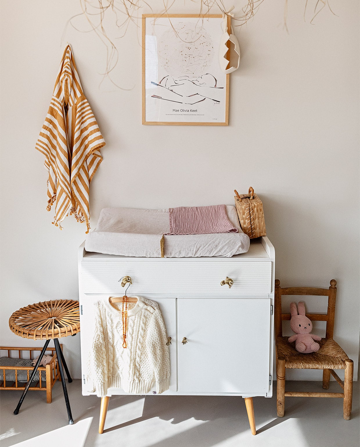 Muurverf Papyrus van Gamma, gietvloer Nature Grey. Hanglamp Couleur Locale, kunst aan muur MrStarsky, strandponcho kind Liewood. Vintage commode Marktplaats, deurknoppen Doing Goods. Poppenbed en kruk van Dirk van Sliedregt vintage. Kinderstoel erfstuk Roberts familie. Rieten koffer kringloop, juten kroon Suussies, naturel kroon en roze deken Archive Store. vtwonen 13-2020 | styling Ilona Jongepier  | fotografie Dana van Leeuwen