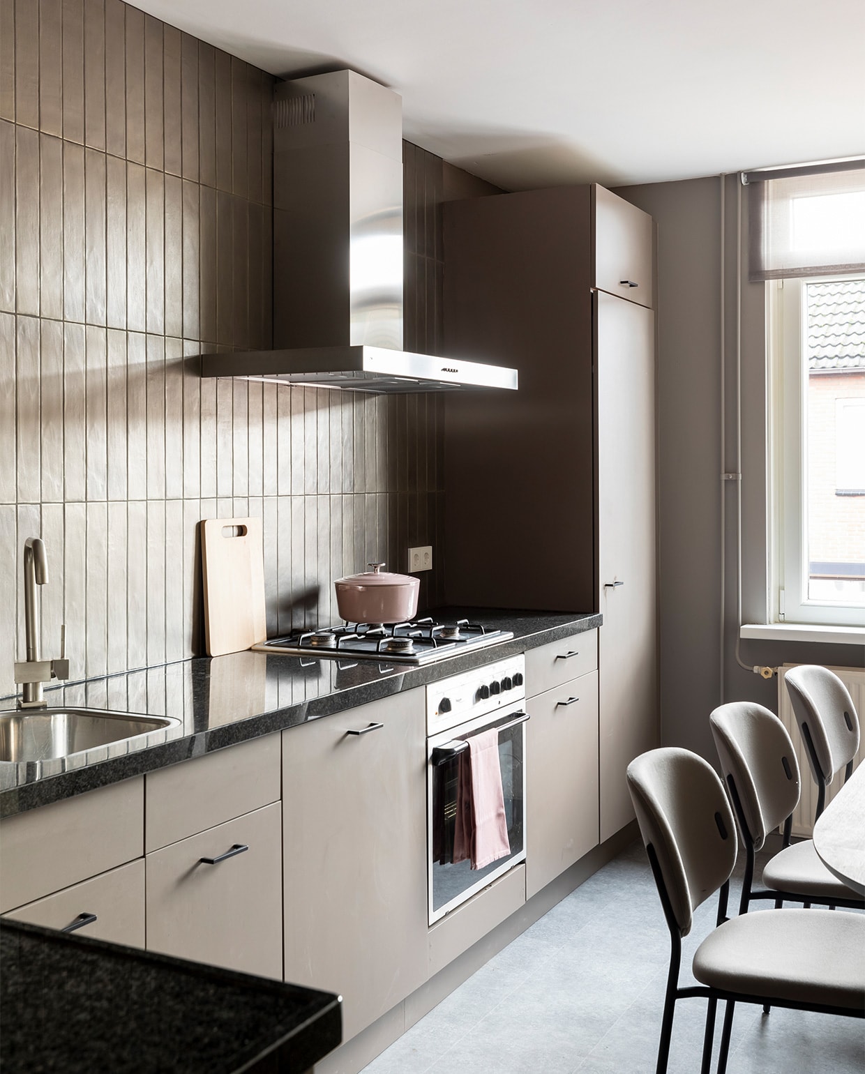 Flexa Creations muurverf bij de ramen Authentic Grey, Flexa Creations lak voor de keukenfronten Sweet Umber (flexa.nl). Wandtegels Marrakesh Bronze mat van vtwonen by Douglas &amp; Jones (douglasjones.nl). Zwarte grepen, per stuk € 3,59 (karwei.nl). Eetkamerstoelen Yo, per stuk € 277,50 (eijerkamp.nl). Wandklok € 165,- (zuiver.com). Braadpan van BK € 79,- (fonq.nl). Vaas van vtwonen € 44,95 (vtwonen.be). Overig privébezit. JA | vtwonen extra aflevering weer verliefd op je huis 6 | styling Fietje Bruijn | fotografie Margriet Hoekstra