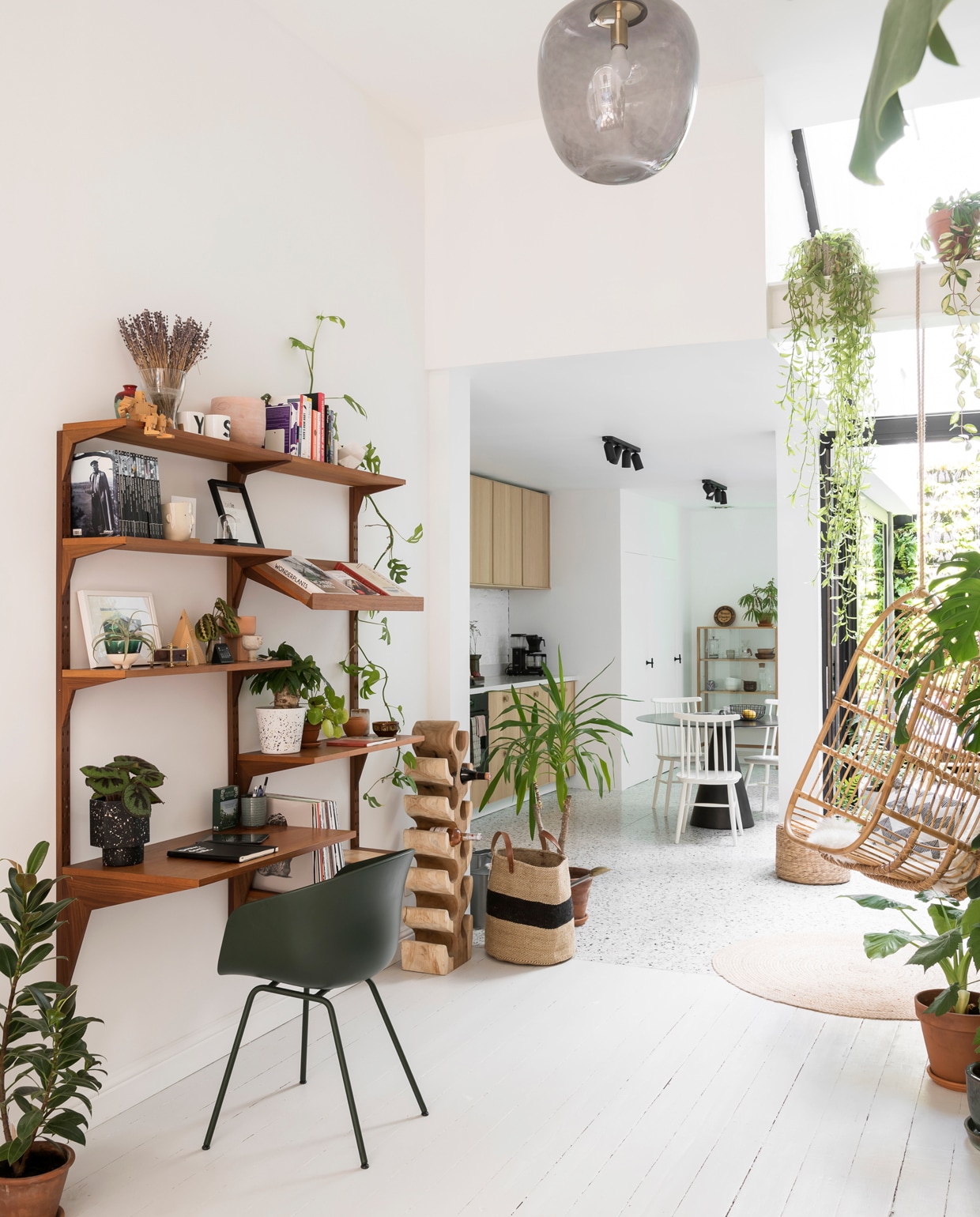 De draagbalk werd bewust niet weggewerkt zodat plantenpotten er een plaatsje konden krijgen. Het mid-century wandmeubel is van Nome Furniture, de bureaustoel van Hay, de hangstoel van Casa en het ronde tapijt van House Doctor. De rotan poef is van Casa. vtwonen 13-2019 | styling &amp; fotografie Jonah Samyn