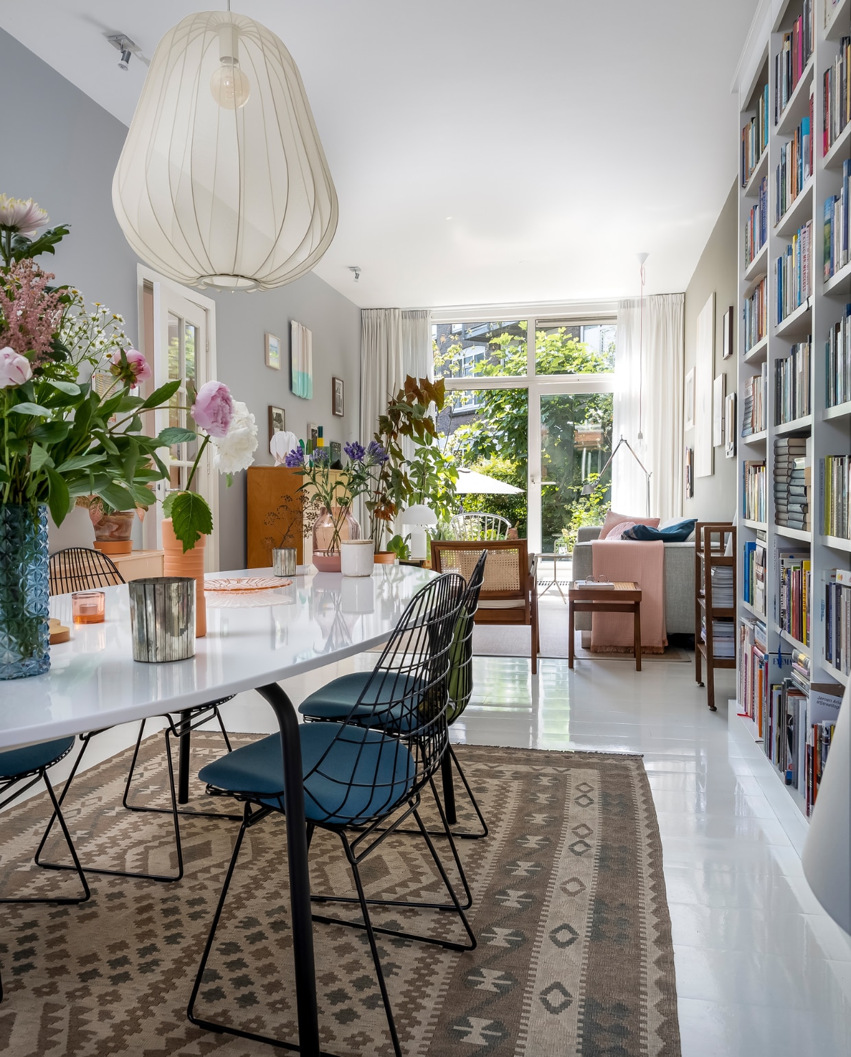 Muurverf Flexa, naam onbekend. Lamp Bolia. Afghaans vloerkleed, herkomst onbekend. Stoelen en houten wandkast Pastoe, eettafel Ikea, blauwe vaas &Klevering, roze vaas Foekje Fleur, sfeerlicht roze Iittala, glazen bord vintage, roze vaas Elevated van Muuto, witte pot geurkaars HKliving. Webbing stoel en bijzettafel Detjer. Boekenkast Lundia. Vloer witte epoxylak over oud parket. Bank Hulshoff, deken Hay, vloerlamp Artemide. Overig herkomst onbekend. vtwonen 10-2022 | fotografie Henny van Belkom