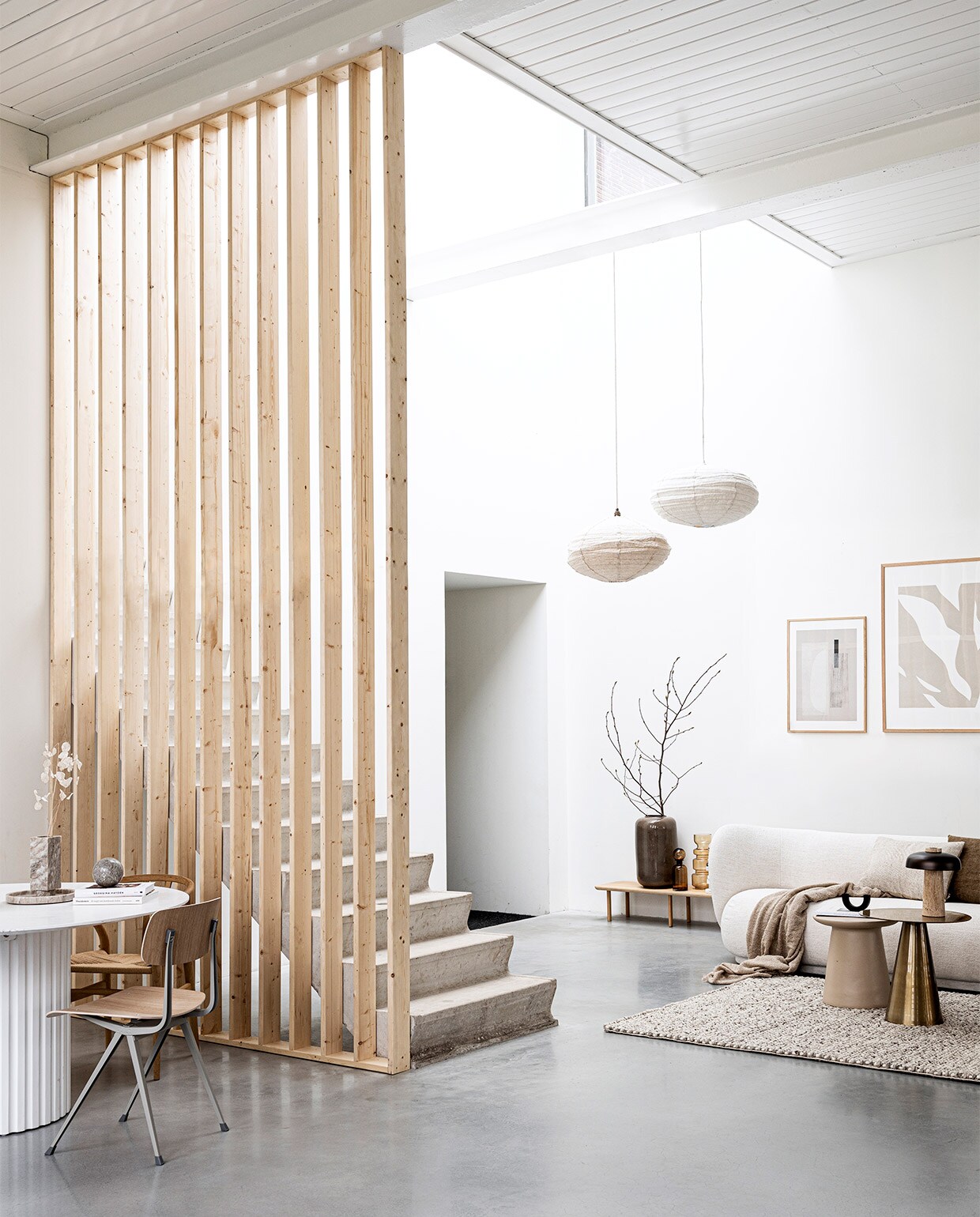 Scheidingswand gemaakt van latten uit vtwonen DIY 09-2020. Laag houten wandmeubel Loof Piled, 24x150x35 cm (hxbxd) € 275,-, zwarte kandelaar Arch van Ferm Living € 45,99 (vtwonen.nl). Marmeren bol € 29,99, bouclé plaid 130×170 cm € 14,99 (hm.com). Grote vaas Jade achter trap € 99,95, bruine glazen vazen achter trap vanaf € 32,95, linnen kussens 40×40 cm € 39,95 en 40×60 cm € 45,- (loods5.nl). Wollen vloerkleed Hjorthede, 160×230 cm € 299,- (ikea.nl). Messing bijzettafel 49×49 cm (Øxh) € 239,-, aardewerken bijzettafel 40×43 cm (Øxh) € 195,- (hkliving.nl). Bouclé 3-zitsbank Rico van Ferm Living, 210x79x81,5 cm (bxhxd) € 3389,- (flinders.nl). Posters: groot Fragments van Moe Made It, 70×100 cm met eikenhouten lijst € 109,- klein Carrarra van Julia Hallström Hjort, 50×70 cm € 89,- met eikenhouten lijst € 69,- (theposterclub.com). Boeken privébezit. vtwonen special 09-2020 | styling Kim van Rossenberg | fotografie Sjoerd Eickmans
