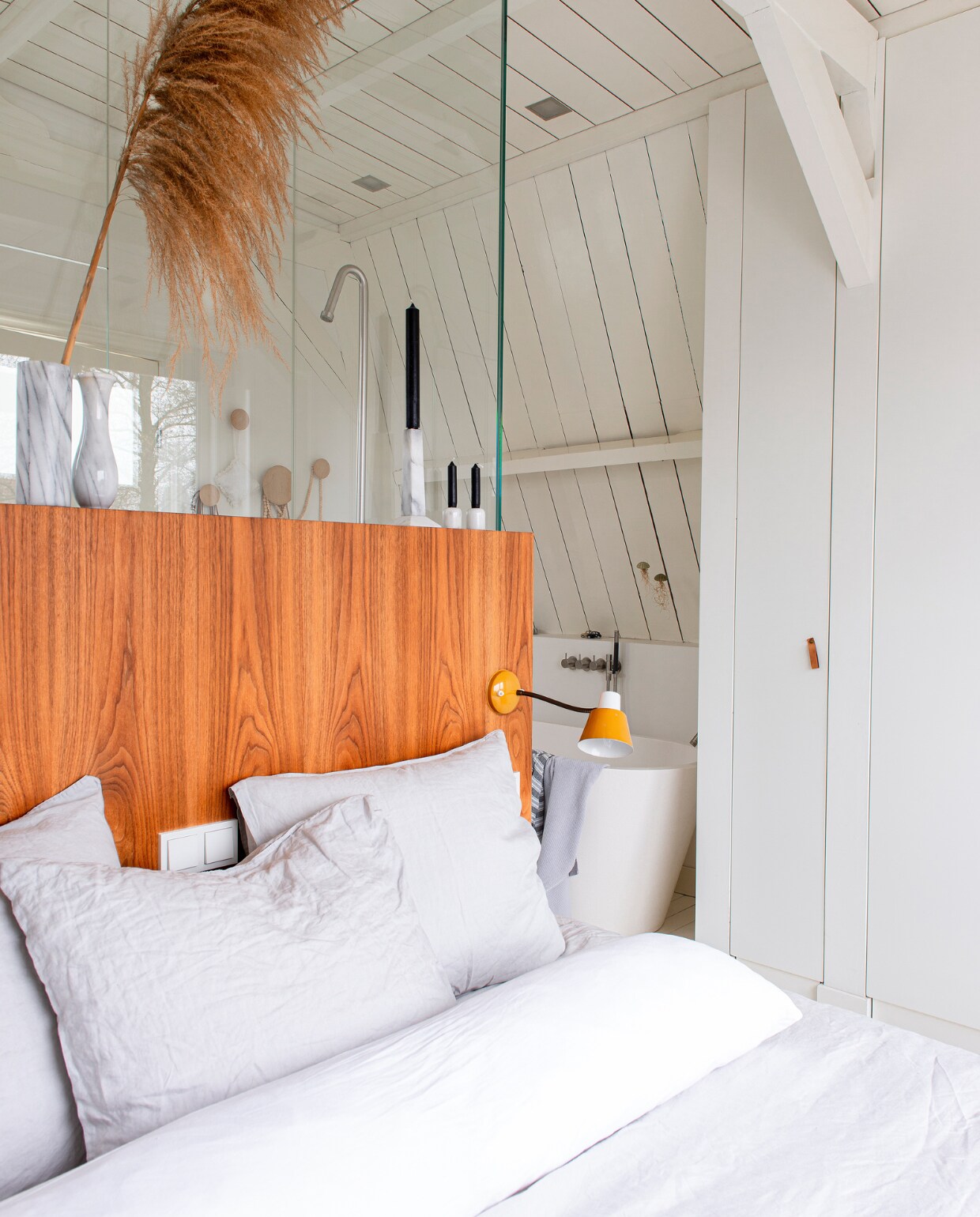 Pluim Miss Bloem, spots Nimbus, vintage marmeren kandelaars en vazen via Sprinkel + Hop, achterwand bed zelfgemaakt, linnen beddengoed van H&amp;m Home, bedlamp vintage, al het houtwerk is geschilderd in RAL 9010. NEE | vtwonen 10-2022 | Productie De Binnenkijkers | Styling Jeske Weel | Fotografie Caroline Coehorst | Tekst Chris Muyres