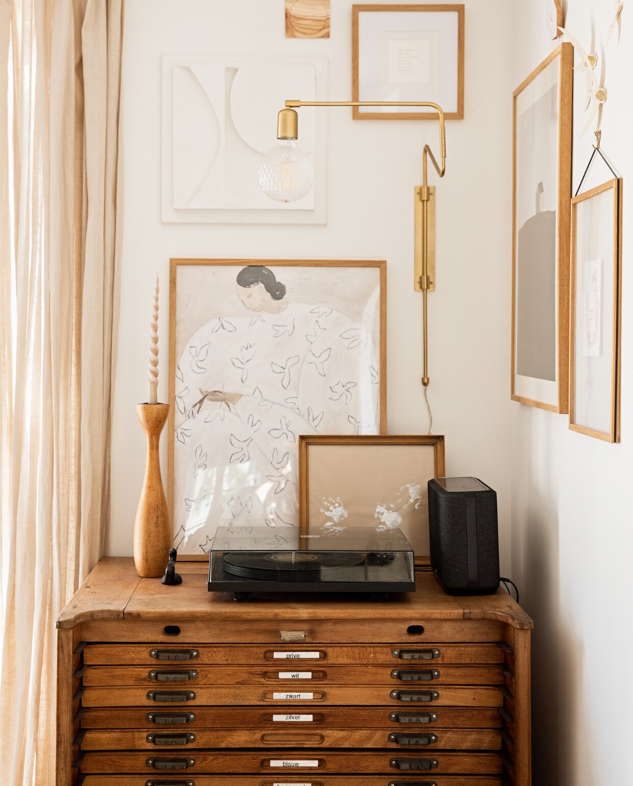 Ladekast Marktplaats, posters PSTR Studio, 3D-kunstwerk en handjes van Koosje zelfgemaakt, klein houten kunstwerk Ruben van der Scheer, kandelaar van kringloopwinkel, wandlamp House Doctor, platenspeler Pro-Ject, speaker Denon. NEE | vtwonen 09-2022 | styling Ilona Jongepier | fotografie Diana van leeuwen | tekst Chris Muyres