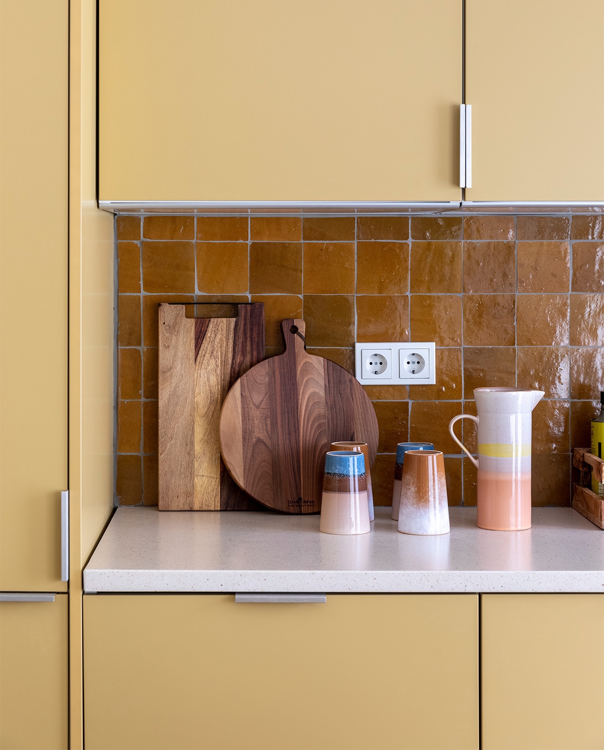 Flexa Creations muurverf om raam Midden Zandstrand (flexa.nl). Keuken op maat gemaakt (k14.nl). Tegels achterwand Zelliges Mustard, per m ? 114,95 (householdhardware.nl). Houten planken van Bowls en Dishes vanaf ? 15,-, koraalkleurige kandelaar van  la ? 30,-, gele kandelaar Flare van Hay ? 49,-, groene glazen vaas van Bloomingville ? 38,90 (vtwonen.nl). Vijzel ? 28,44 (bowls-dishes.nl). Kan ? 29,95 en theemokken ? 11,40 van HKliving (eijerkamp.nl). Kunstwerk Neutrale collage van Laura Horn ? 50,- (werkaandemuur.nl). vtwonen weer verliefd op je huis extra seizoen 15, aflevering 3 | styling Marianne Luning | fotografie Margriet Hoekstra