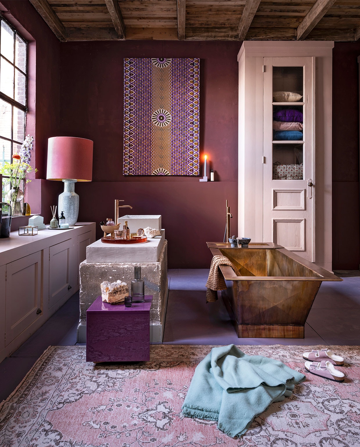 Badkamer aubergine , , Op de muur krijtverf Moorland per liter € 39,30, op de vloer lakverf Bohemian per liter € 61,40, verf op de kasten lakverf Old Rose per liter € 61,40 (pure-original.nl). Kasten, beide op maat gemaakt, prijs op aanvraag, wasbak prijs op aanvraag (com-anders). Bad in gepatineerd messing, 2000x815x555 cm (lxbxh), prijs op aanvraag bij de koperslagerij (juliusballer.nl). Losstaande kraan in brons € 2050,-, wastafelkraanin brons € 525,- (jee-o.com). Plexiglazen tafel van HKliving € 195,- (vtwonen.nl). Doek van waxstof item nr. VL40850.365.02 vanaf € 54,95 (vlisco.com). Vloerkleed € 495,- (rozenkelim.nl). Lampenkap € 375,-, lampenvoet € 396,- (polspotten). Glazen vaas van Menu € 69,95, glazen vaas op vensterbank van Bloomingville € 38,99, bord van HKliving € 17,50, waterkan van Ferm Living € 35,-, glazen van Ferm Living per 4 € 35,-, stenen zeepbakje van Ferm Living € 119,-, wafel handdoek van Ferm Living € 39,- (vtwonen.be). Geel glazen object kwart cirkel van HKliving € 59,95 (deens). Mintgroen keramisch object € 69,95, geurstokjes € 26,95, oranje glazen plateau € 259,- (hkliving.nl). Sieradendoosje € 19,-, kandelaar € 19,95, wollen deken van Hay € 75,- (eijerkamp). Schaaltje op 3 poten € 30,- (101cph.com). Overig privébezit. vtwonen 10-2020 | styling Marianne Luning | fotografie Stan Koolen