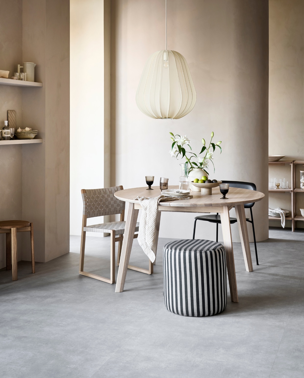 pvc-vloer Basic XL, kleur Light Grey, 91,4×91,4 cm, dryback per m² € 67,95 (alleen verkrijgbaar als dryback). M.m.v. pure-original.nl (muurverf Fresco in kleur Canvas), vtwonen.nl (lamp van Bolia, houten sidetable van Vestbjerg, zwarte eetkamerstoel van Hay), demachinekamer.nl (eettafel), designtales.nl (eetkamerstoel met geweven zitting, houten kruk, theepot, schaal), sofacompany.com (poef), zarahome.com (glazen karaf, borden, bestek, transparant glaswerk, glazen eierdop, glazen voorraadpot, witte vaas), loods5.nl (bruine wijn- en drinkglazen, theedoek), arket.com (aardewerk met diagonale strepen), hmhome.com (houten etagère, linnen servet), sissy-boy.com (stapel van beige keramieken pastaborden). Overig privébezit. vtwonen 10-2022 | productie Tanja Saarberg  | styling Sanne Ketelaar | fotografie Sjoerd Eickmans