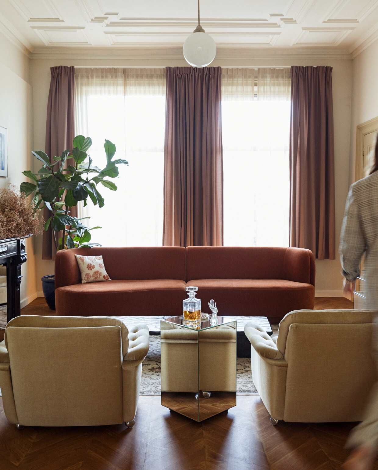 Gordijnen Jan Sikkes. Kamerplant, hanglamp en fauteuils Marktplaats. Vloerkleed Zuiver. Droogbloemen Flower Cloud van Yoko Negi. Bank Sofa Company. Kussen De Weldaad. Spiegel-bijzettafel Zara Home. Overig onbekend. NEE | vtwonen BK8- 5 2022 | styling Ilona Jongepier |  fotografie Dana van Leeuwen | tekst Jana Voyvodich