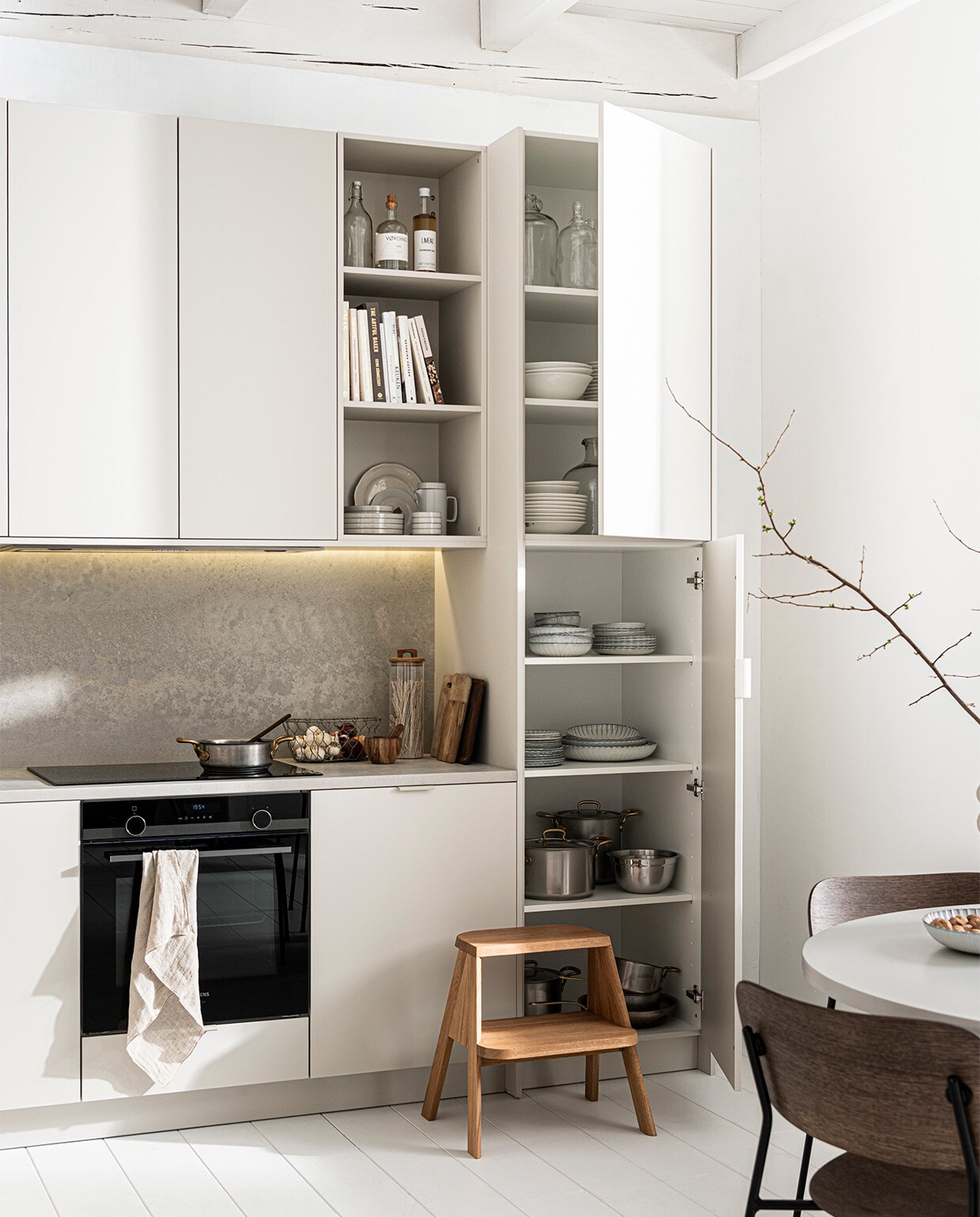 Keuken Basic Greige zoals getoond, exclusief accessoires. M.m.v. sjostrandcoffee.nl (koffiezetapparaat en melkopschuimer), menuspace.com (eetkamerstoel Co), com-anders.nl (eettafel), sissy-boy.com (vaas), vtwonen.nl (servies op tafel van Serax, keukenrek van Ferm Living), thefinestore.com (dienblad en kopje). Overig privébezit. vtwonen 12-2021 | styling Kim van Rossenberg | fotografie Sjoerd Eickmans
