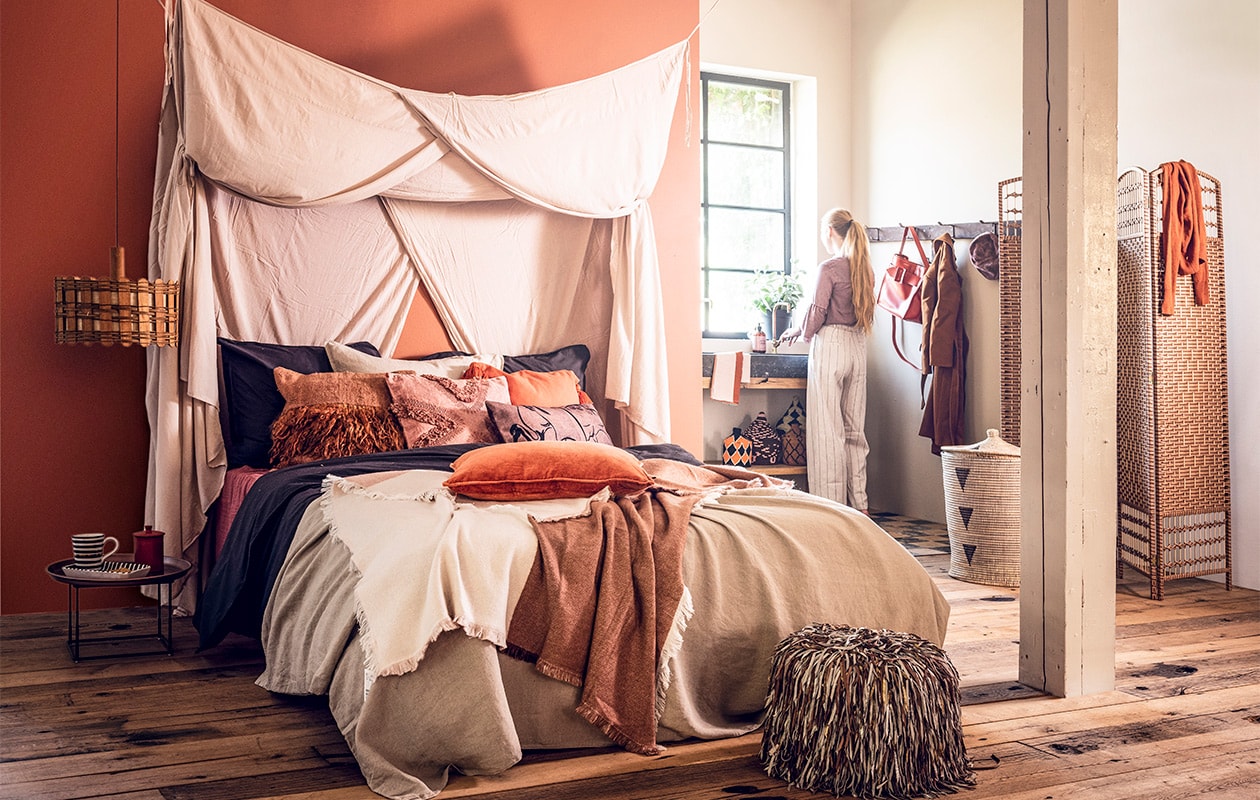 Muurverf Tuscan Red van Little Greene, per liter € 49,- (De Ru). Laken € 12,99, grijs dekbed € 49,99, beige dekbed € 49,99, oranje kussen met kwasten € 9,99, egaal oranje kussen € 7,99, plaid met diverse kleuren € 39,99, handdoek € 9,99 (H&amp;M Home). Oranje kussen met rafels € 75,- (Brecht Murré Atelier). Verwassen oranje kussen € 35,-, kamerscherm € 87,95 (De Weldaad). Kussen met bloemenprint € 24,95 (HK Living). Eenpersoons hemelbedlaken € 180,- (Archive Store). Nachtkastje € 678,- (Homestede). Mok € 24,95, bord € 35,-, oranje bakje € 19,95 (MaisonNL). Houten lamp € 125,- (Neef Louis). Poef met franjes € 169,-, Marokkaanse manden klein € 39,-, groot € 79,-(Household Hardware). Wasbak met badkamerkast, prijs op aanvraag, kraan € 100,- (Jan van IJken Oude Bouwmaterialen). Zeep € 9,99 (Pieter &amp; Tosch). Kapstok vanaf € 45,- (Combitex). Pet € 24,95, broek € 44,95, top € 44,95 (Things I Like Things I Love). Tas € 219,99, jas € 379,99, trui € 99,99 (Fabienne Chapot). Plant privébezit. vtwonen 09-2018 | styling Liza Wassenaar | fotografie Sjoerd Eickmans