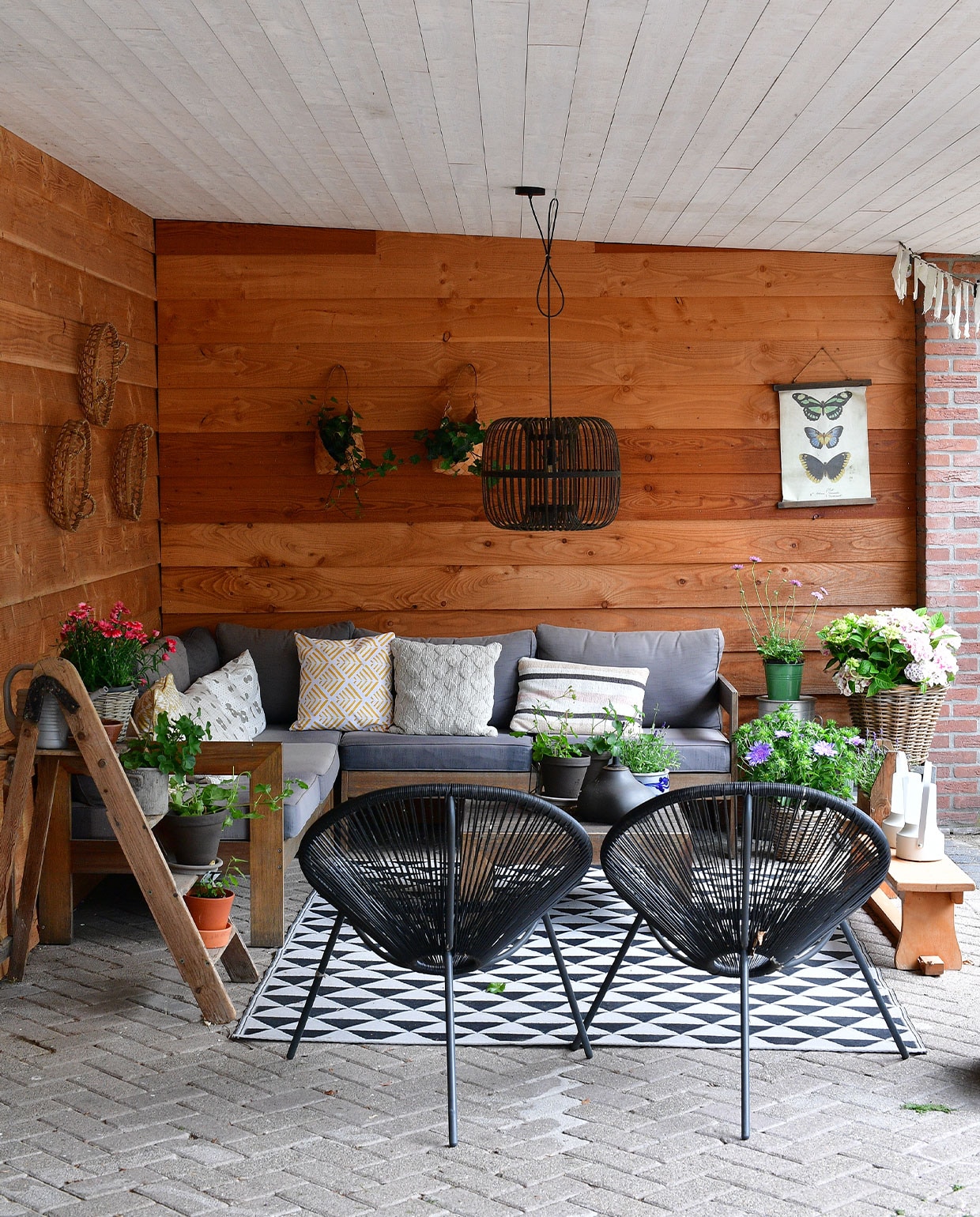 De veranda van ’t Heide Huisje is uitgevoerd in Douglas-hout. Een oude keukentrap doet dienst als plantentafel. Loungeset en stoelen Karwei, lamp De Panhoeve, vloerkleed Ikea, dienbladen als wandversiering Kwantum, gymbank kringloopwinkel, overig onbekend. vtwonen special Tuin 5 | fotografie Sietske de Vries | tekst Monique van der Pauw
