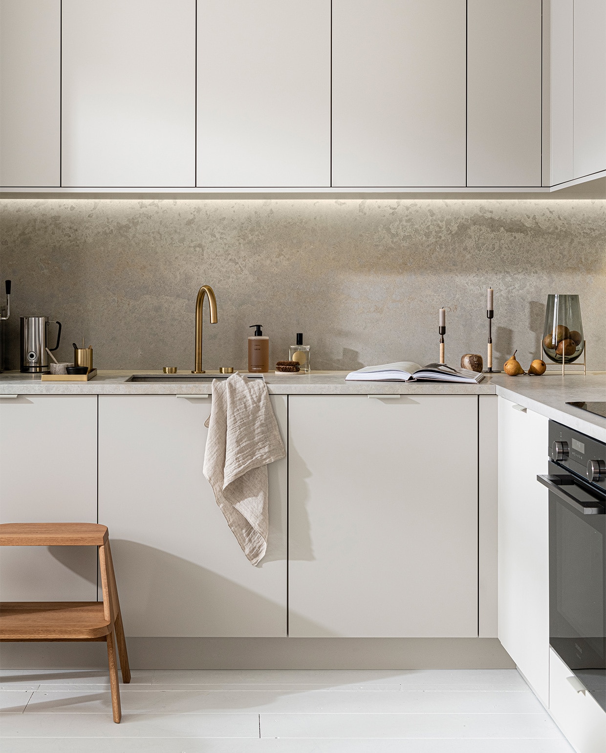 Keuken Basic Greige, vanaf € 21.500,- M.m.v. thefinestore.com (houten krukje van Hay, messing dienblad en beker van Ferm Living, bronzed brass kandelaren Duca van Menu), flinders.nl (vaas van gerookt glas op messing pootjes van Menu), kikubari.nl (spray van Lingua Planta), vtwonen.be (theedoek uit de vtwonen collectie), skins.nl (handzeep Suede Byredo), sjostrandcoffee.nl (melkschuimer). Overig privébezit. vtwonen 03-2021 | styling Kim van Rossenberg | fotografie Sjoerd Eickmans