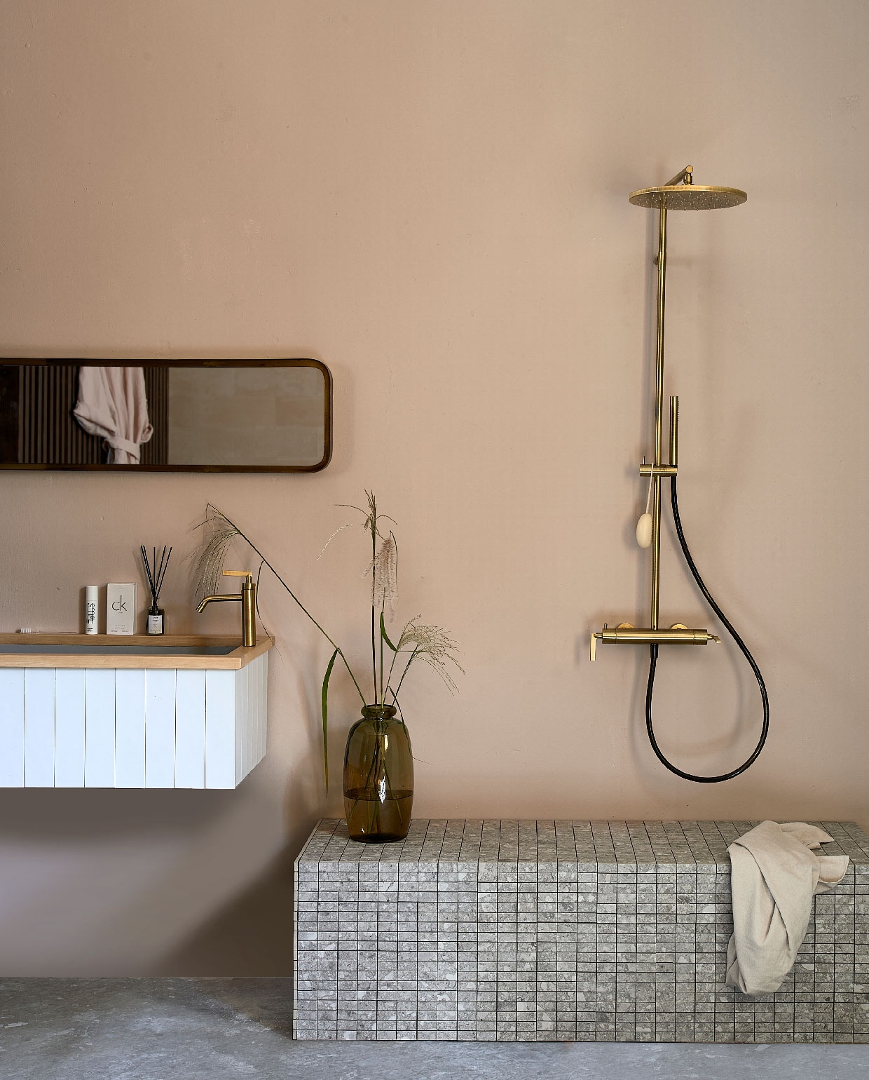 Wastafel op maat gemaakt en betegeld met wandtegel Mediterranea Calpe Blanco van vtwonen, 7,5×30 cm € 78,85 per m², Composite Mozaiek Light Grey van vtwonen, 30×30 cm € 26,00 per stuk. (vtwonentegels.nl). Douchekraancombinatie Grip in Bronze van vtwonen € 2188,- (vtwonen.be). Spiegel € 149,- (basiclabel.nl). Handdoek € 8,99 (hm.com). Bruine vaas € 25,- (loods5.nl). Overig privébezit. vtwonen 10-2020 | styling Fietje Bruijn | fotografie Dennis Brandsma