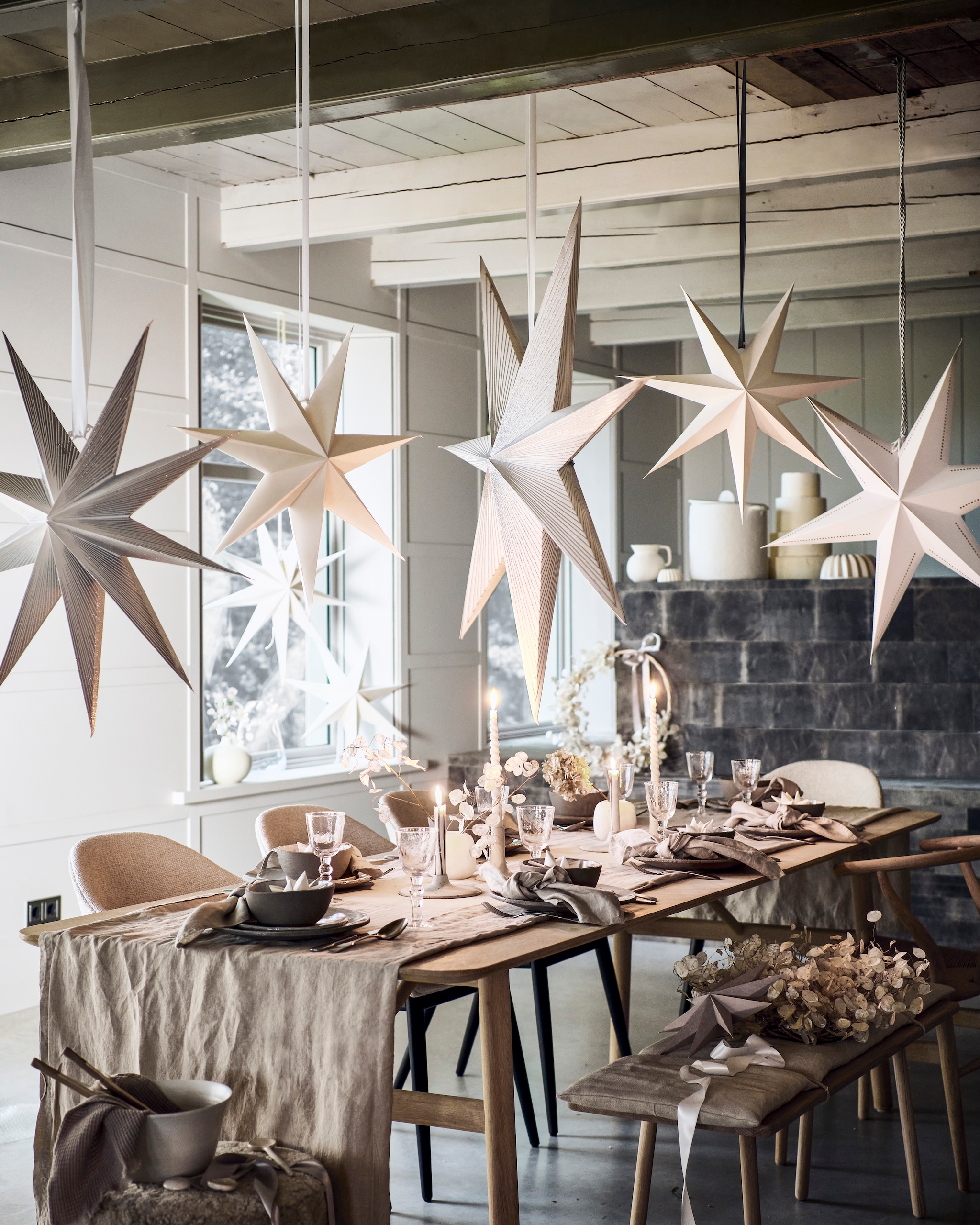Op en boven tafel: linnen tafelkleed € 39,99, linnen servetten, set van 2 € 9,99, witte papieren kerststerren in kommen, per stuk € 3,99, hangende witte sterren, per stuk € 7,99 (hm.com). Dinerbord per stuk € 37,-, ontbijtbord per stuk € 14,75, kom per stuk € 14,75 (serax.com). Wijnglazen, per stuk € 12,50, stonewashed zilveren bestek, per stuk vanaf € 6,95, witte gedraaide kaarsen, per stuk € 3,50 (paviljoennoord.com). Keramieken kandelaars plat, hoog (letoile.store). Albasten vazen, per stuk € 24,99 (sissy-boy.nl). Papieren sterren met zilveren strepen, vanaf € 18,75, witte ster met geperforeerde accenten € 18,75 (bungalow.dk). Interieurontwerp Piet-Jan van den Kommer (vandenkommer.nl). Om de tafel: bouclé kruk van Menu, gestoffeerde eetkamerstoelen van Menu, per stuk (designtales.nl). Witte schaal van Studio Ro Smit (factor-ij.amsterdam). Wafeldoek € 7,99 (hm.com). Beige keramieken lepels, per stuk vanaf € 4,99 (sissy-boy.nl). Witte porseleinen lepels, per stuk vanaf, eikenhouten eettafel, houten bank met linnen kussenzitting, houten eetkamerstoel (letoile.store). Grijze papieren ster € 8,- (bungalow.dk). Kransen van judaspenning, vanaf € 39,- (tuinvanjudith.wordpress.com). In de vensterbank en op het aanrecht: keramieken bolvaas € 56,90 (letoile.store). Glazen vaas € 19,99, witte papieren sterren, per stuk € 7,99 (hm.com). Witte keramieken kan € 24,99 (sissy-boy.nl). Tulbandvormen, per stuk vanaf € 11,99 (zarahome.com). Papier-maché pot met deksel € 140,- (paviljoennoord.com). vtwonen 12-2021 | styling Danielle Verheul | fotografie Sjoerd Eickmans | tuin van Judith (groenstylist) | assistentie Niels Kist, Kula van den Broek