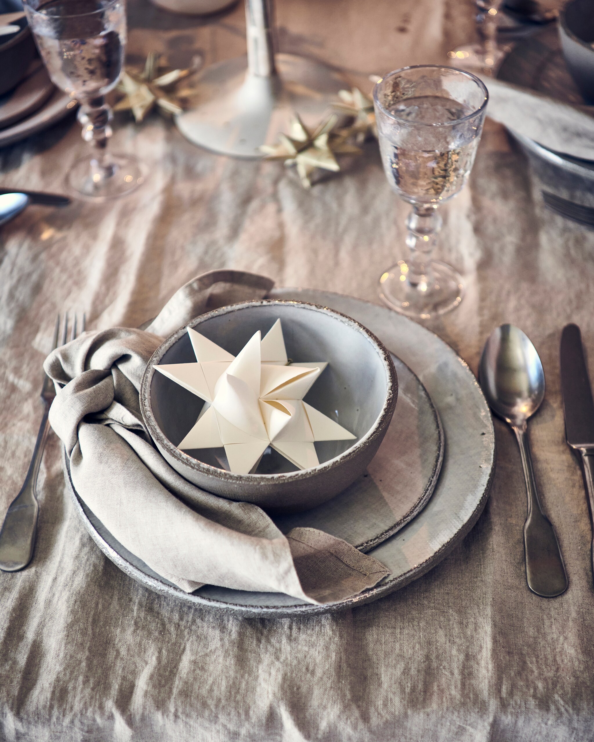 linnen tafelkleed € 39,99, servet, set van 2 € 9,99, witte papieren ster € 3,99 (hm.com). Serviesgoed, per stuk vanaf € 14,75 (serax.com). Stonewashed zilveren bestek, per stuk vanaf € 6,95, wijnglazen, per stuk € 12,50 (paviljoennoord.com). Keramieken kandelaar, beige papieren sterren met gouden stippen, set van 3 (letoile.store). vtwonen 12-2021 | styling Danielle Verheul | Fotografie Sjoerd Eickmans | Tuin van Judith (groenstylist), assistentie Niels Kist, Kula van den Broek