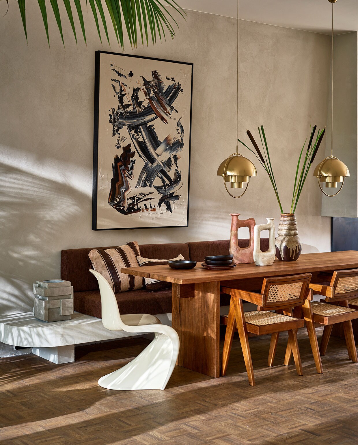 Abstract schilderij van Patrick van Riemsdijk (patrickvanriemsdijk.com). Op maat gemaakte tafel van frakéhout, prijs op aanvraag (@takumi_interior). Tamegroute-vaas, klein € 115,-, groot € 138,- (householdhardware.nl). Houten armstoelen Detjer Office Chair, € 425,- (casagitane.com). Hanglampen Multi Lite Pendant Large Brass van Gubi, € 839,- (nordicnew.nl). Vintage jaren 70-vaas € 50,- (vandijkenko.nl). Witte kunststof stoel Panton Chair van Verner Panton uit 1974, € 750,- (neeflouis.nl). Donkerbruine keramische borden Home Chef, diep € 16,95, plat € 17,95 (hkliving.nl). Betonnen wijnkoeler € 149,- (serax.com). Bruin/beige gestreept kussen 50×60 cm € 149,-, bruin/beige gestreept kussen, 60×40 cm € 149,- (couleurlocale.eu). vtwonen 09-2021 | styling Cleo Scheulderman | fotografie Jeroen van der Spek | assistentie Krystel Jane Robinson