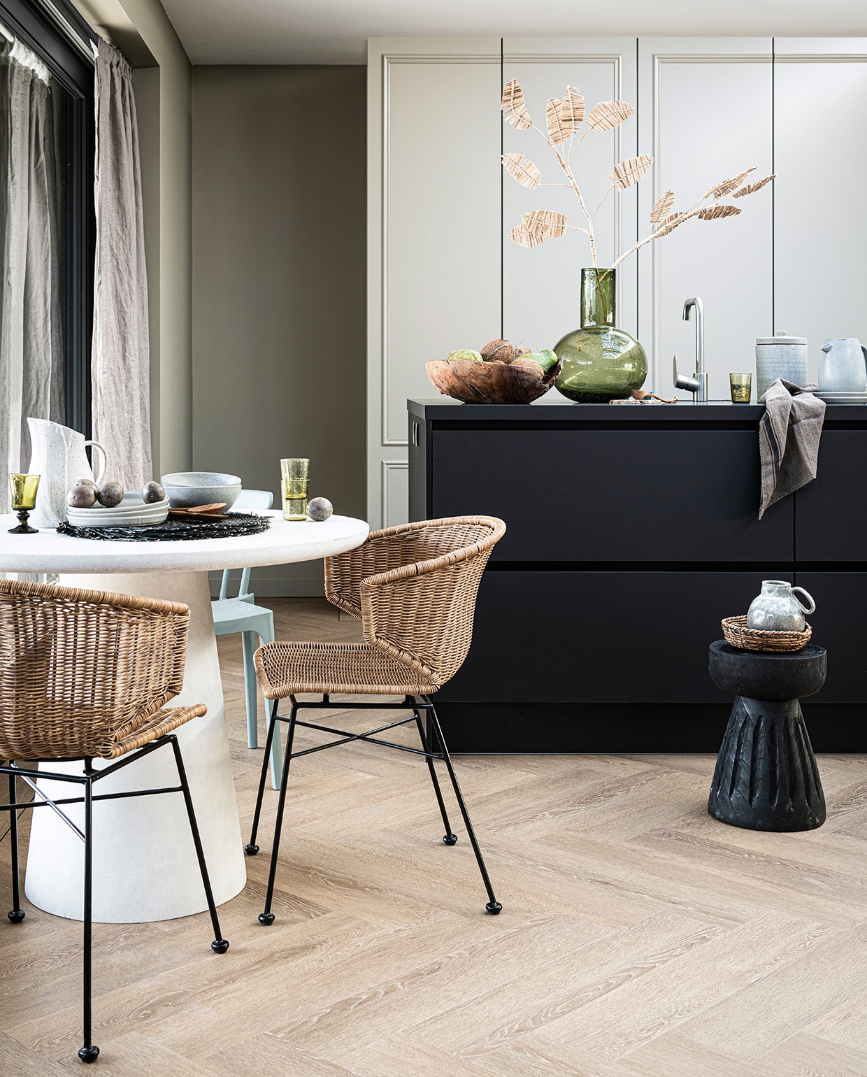 PVC-Vloer Herringbone Sun Kissed, visgraat 76,5×15,3 cm dryback per m² € 44,95, 75×15 cm click per m² € 57,95. Ook in de kleuren Natural, Polar en Roasted. M.m.v. basiclabel.nl (eettafel, eetkamerstoelen en houten kruk van Woood), vtwonen.nl (grijze borden, schalen, kom, placemats, stenen pot met deksel, kruik met handvat, alles van Bloomingville), sissy-boy.com (grijze kan wit geverfd, houten schaal, rotan takken), hm.com (mand, linnen gordijn), paviljoennoord.com (groen wijnglas, groene waterglazen, houten bestek, groene glazen vaas, theedoek). Overig privébezit. vtwonen 06-2021 | productie Tanja Saarberg | styling Danielle Verheul | fotografie Sjoerd Eickmans