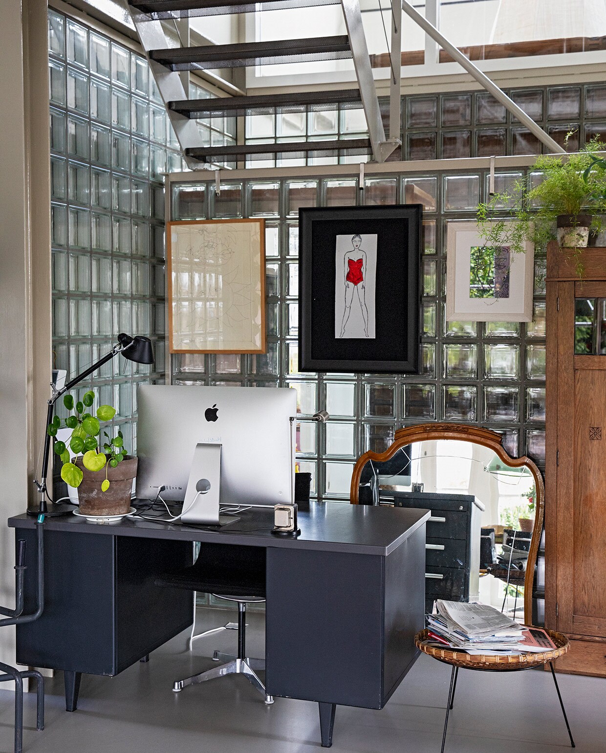 Werkplek van Michiel onder de trap. Oud Gispen-bureau van Karens opa. Leeslamp Artemide. Stoel Vitra. Krantenbak, spiegel en kast vintage. Aan de wand van glazen blokken v.l.n.r.: kunstwerk van Truyen (familiestuk Michiel), tekening van Karen, kunstwerk gekocht in Istanbul. vtwonen 07-2021 | styling Ilona Jongepier | fotografie Dana van Leeuwen