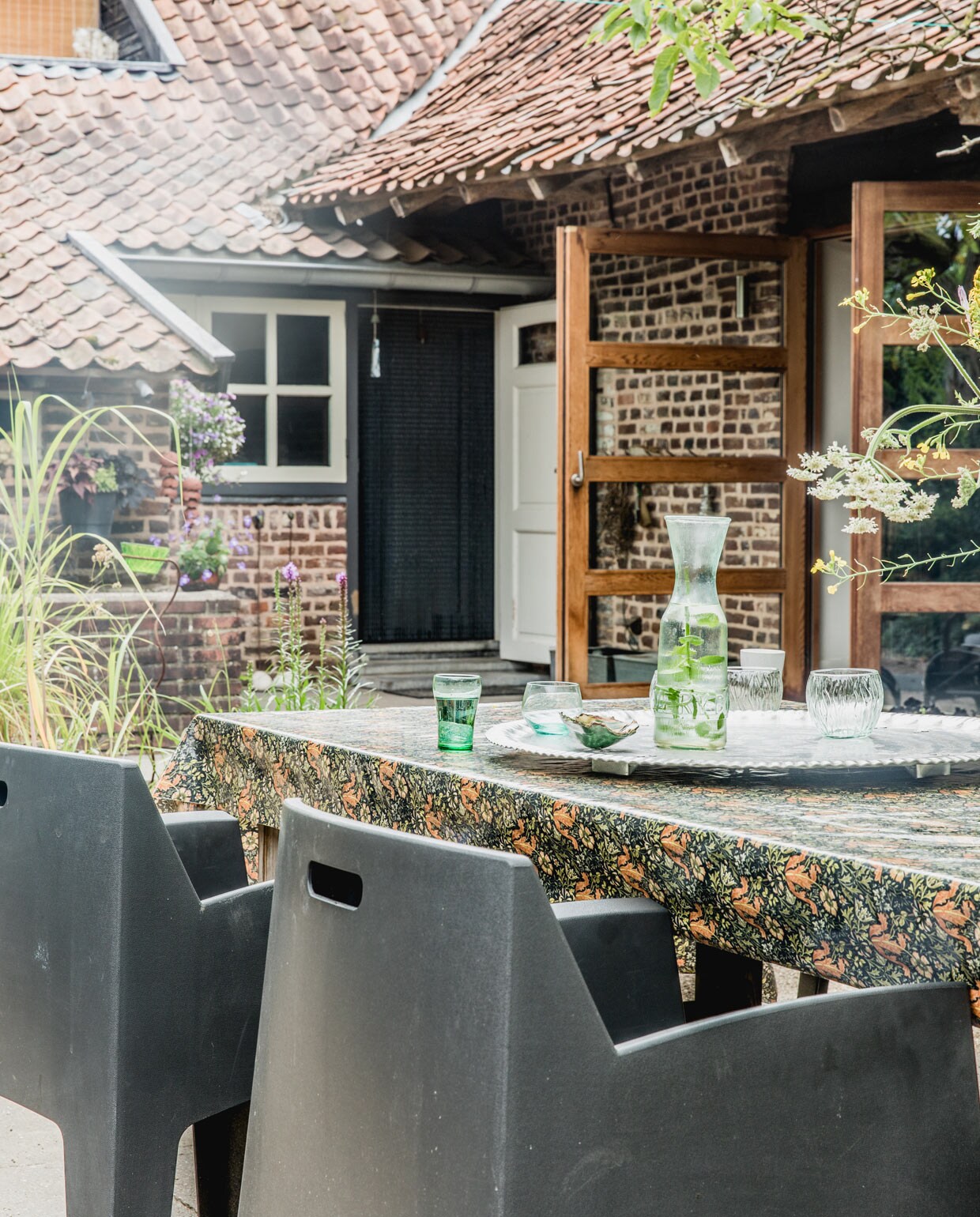 Houten buitentafel gemaakt door Jan. Weerbestendig tafelkleed William Morris. Tuinstoelen Leen Bakker. Overig herkomst onbekend. vtwonen 05-2021 | productie Features &amp; More | styling Wilma Custers | Fotografie Ivar Janssen | Tekst Erica de Graaf