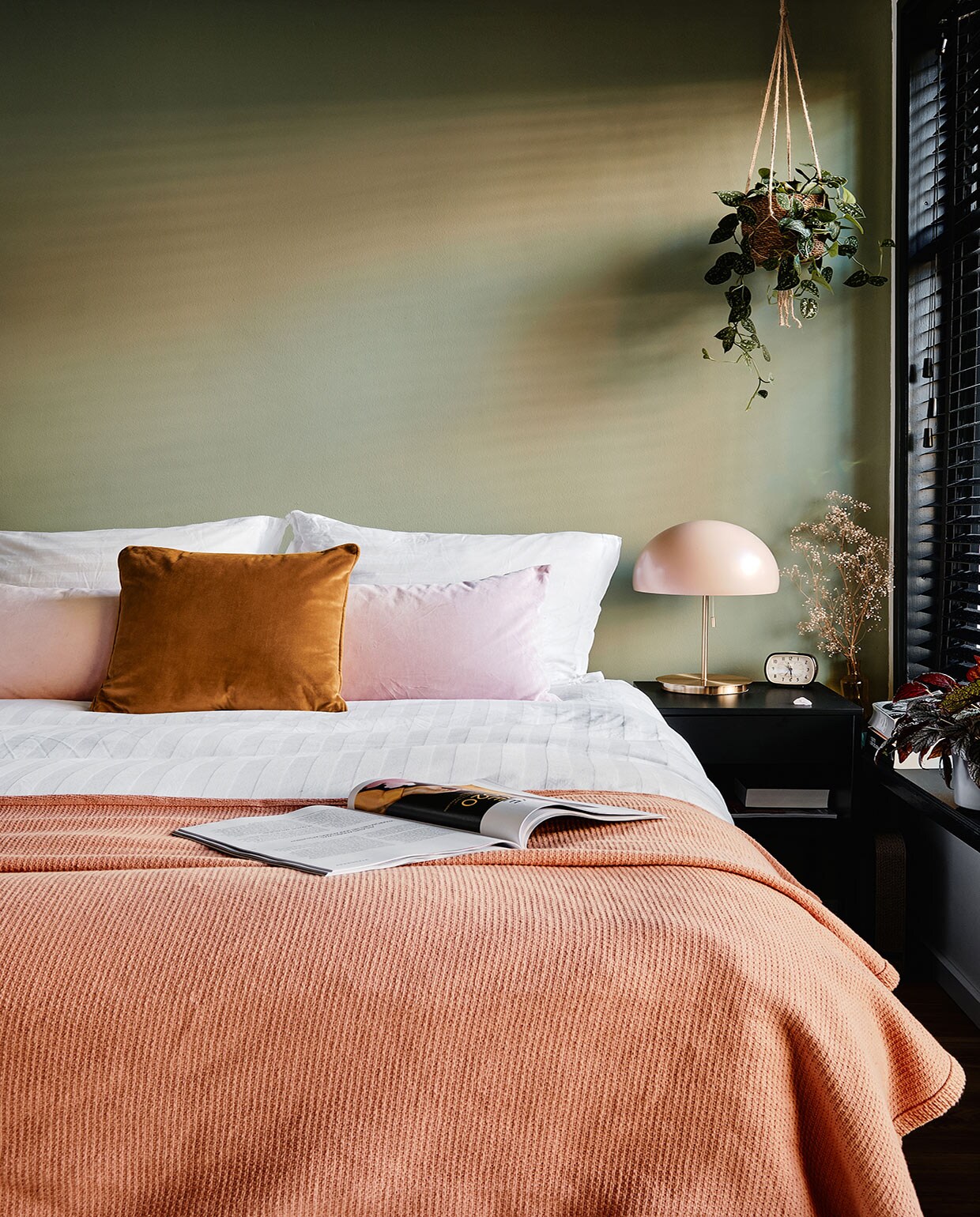 Bed, kussens en vakkenkast Ikea. Beddengoed Hema, sprei Made. Hangplant, bloempot, waxinehouders De Balkonie. Nachtlamp Made, Wekker kringloop. vtwonen 02-2021 | Productie Coco Features | Fotografie Roos Oosterbroek