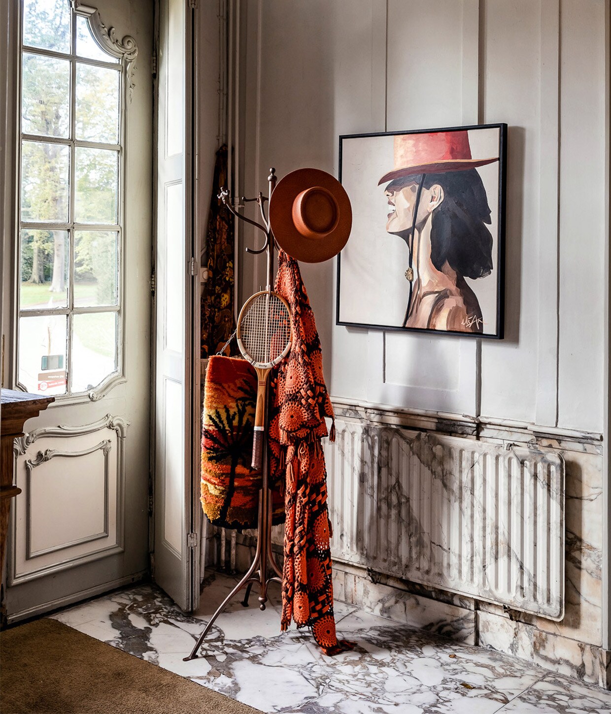 Achter de voordeur een marmeren vloer en balustrade met trompe-l?oeil effect: pas in tweede instantie wordt de radiator zichtbaar achter de klassieke Thonet-kapstok met vintage stukken. Het schilderij is The Red Hatter van Eliane Douglas. vtwonen 01-2021 | Productie en Tekst Roos Stalpers &amp; Fee van ?t Veen | Fotografie Ernie Enkelaar