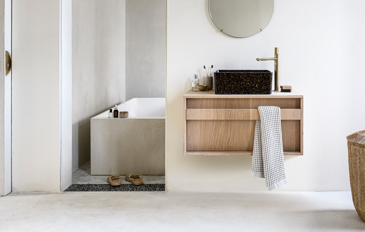 Kleur op de muur Mikonos van We Are Wow Makers, prijs op aanvraag (anoukb.com). Messing spiegel van Moebe, 50 cm (Ø) € 175,-, wastafel van houtcomposiet bestaande uit echte houtsnippers WB07 in kleur Root € 719,95 (aedamanthony.nl). Hoge wastafelkraan van geborsteld messing € 199,- (tworooms.nl). Bad ontwerp van Anouk B in samenwerking met Not Only White, prijs op aanvraag (anoukb.com). Zeep € 10,95 (zeeplokaal.nl). Handdoek Mova van Marc O’Polo 50×100 cm € 14,95, schaaltje Juras € 5,90 (vtwonen.be). Parfum van Le Labo, vanaf € 105,- (skins.nl). Tandenborstelbeker € 7,99 (hm.com/nl). Tandenborstels van Meraki € 6,95 (Loods5.nl). Slippers € 29,95 (zarahome.com). Overig privébezit. vtwonen 01-2021 | Styling Kim van Rossenverg | Uitvoering Richard van Meerveld | Fotografie Sjoerd Eickmans