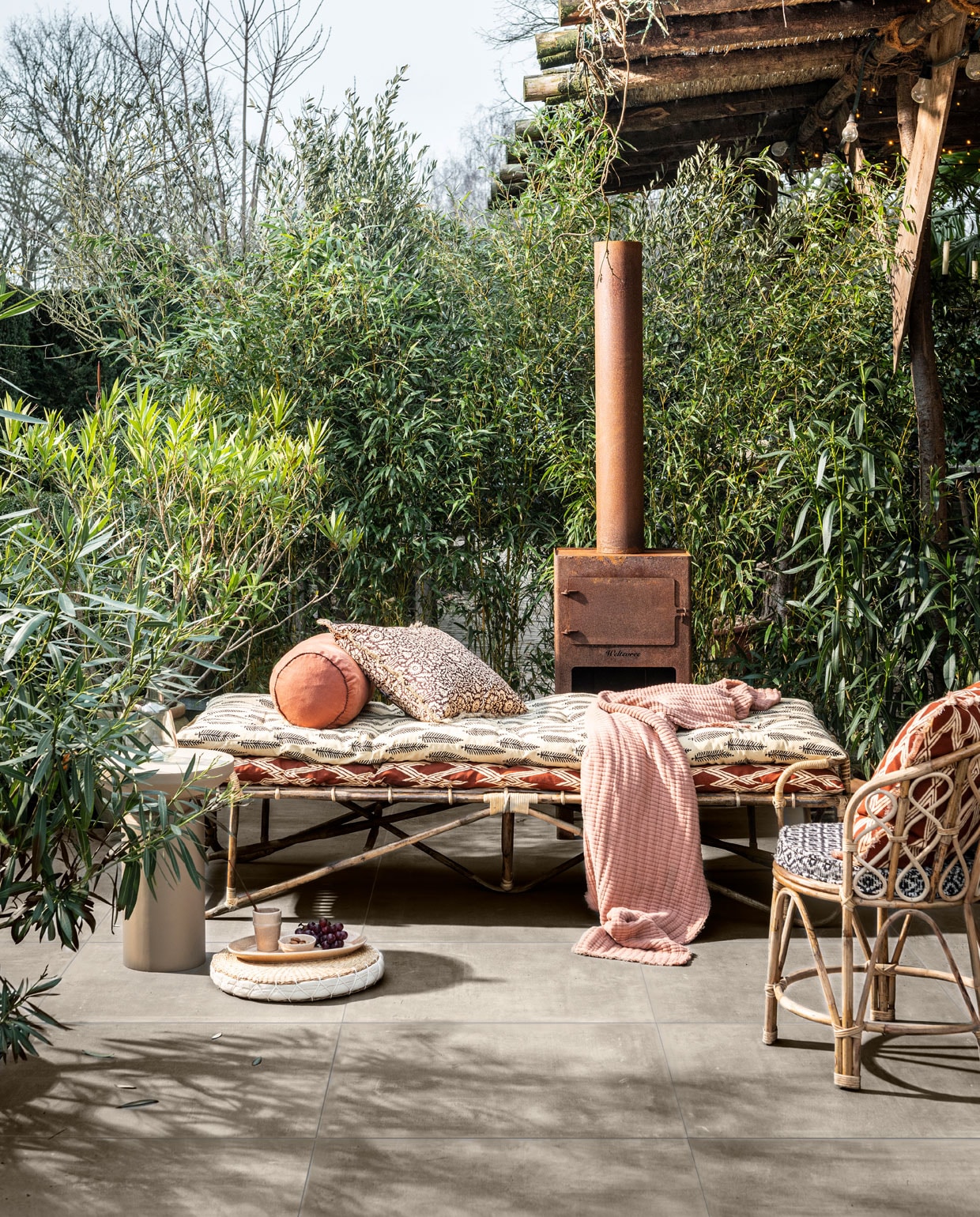 Buitentegels , 70x70x3,2 cm (lxbxh) per m² € 69,95.m.m.v. madamstoltz.dk (bamboe daybed, stoel, kussens, rond gevlochten kussen, servies, plaid), nordal.eu (ronde bijzettafel), weltevree.eu (buitenoven).