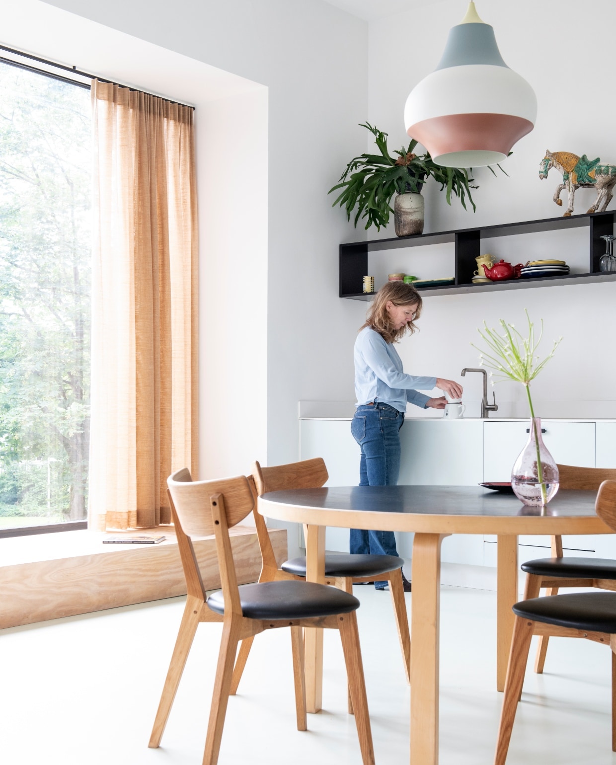 Keukenkasten Kvik. Kleur blauw Pale Powder van Farrow &amp; Ball. Tafel van Artek. Stoelen Ami van Rowico. Erboven Cirque hanglampen van Louis Poulsen. Blauw-roze vaas is een cadeau. Glazen vaas rommelmarkt. Stof gordijnen Jules Sienna van The Alfred Collection. Los element van vintage Artifort bank. Keuken: hanglampen Decovry. Zwart vaasje cadeau gekregen. Het houten art deco tafeltje kreeg Clementine van haar moeder toen ze net op kamers was, het kunstwerk erboven is van Alf Slegers. Fruitschaal van een brocante. vtwonen 03-2020 binnenkijken special | Productie InsideHomePage| Styling Kristel de Jong | Fotografie Louis Lemaire | Tekst Caroline Westdijk