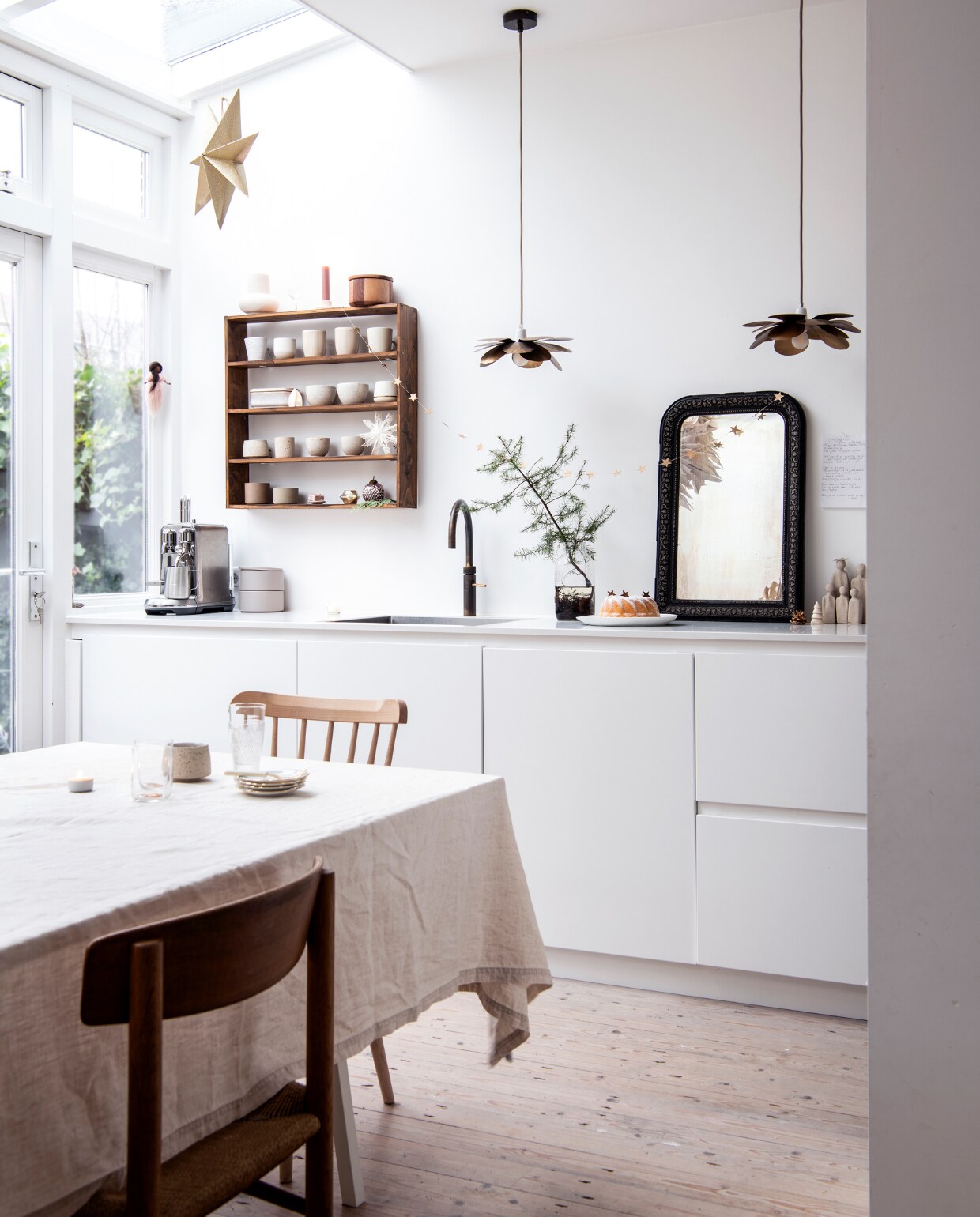 Keuken Kvik, kraan Messing Patina Classic Fusion gecombineerd met de Cube van Quooker, lampen Caravane, spiegel Jolandelijk, wandrek zelfgemaakt, kerststerren Alles in wonderland. Eettafel: schragen Hay, blad Pontmeyer, zelf geschilderd en bevestigd. Tafelkleed H&amp;M Home, stoelen J39 Mogensen via Marktplaats, licht houten stoel Dille &amp; Kamille. vtwonen 13-2022 | productie Insidehomepage | styling Myla Griese | fotografie Louis Lemaire