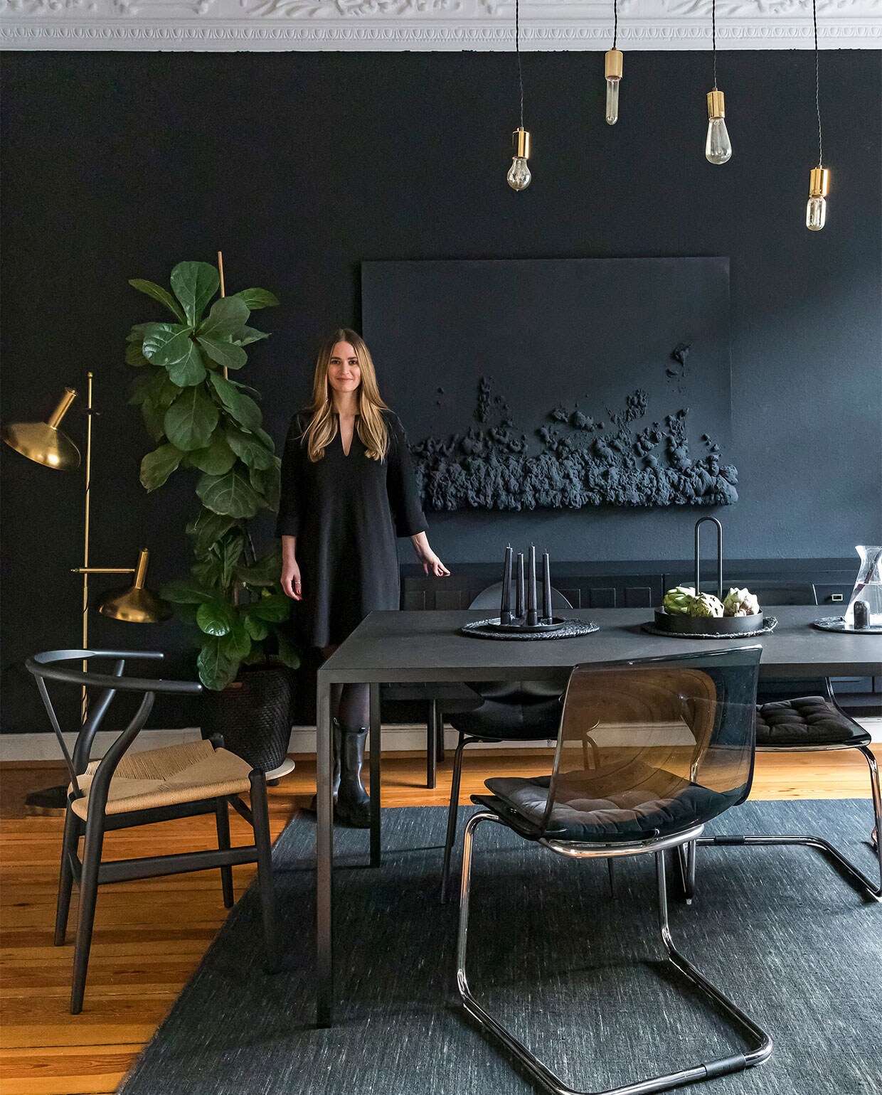 Muurverf Kleines Schwarz Schöner Wohne Farbe. Gouden vloerlamp tweedehands. Wandkunstwerk door Sabrina gemaakt. Zwartgeverfd dressoir erfstuk. Eettafel op maat gemaakt. Stoel links CH24 Wishbone Carl Hansen, overig tweedehands verzameld. Vloerkleed Rugvista. Overig onbekend.