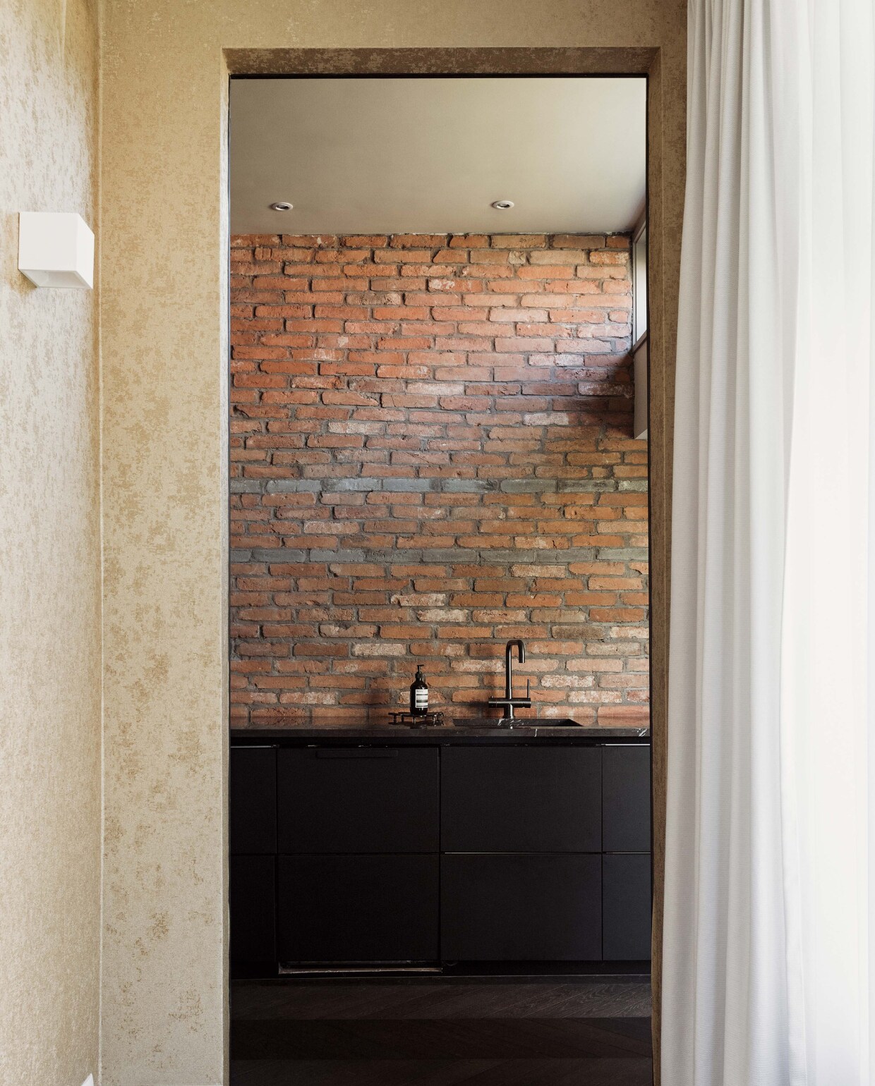 Behang Versace. Wandlamp Rietveld Licht. Steenstrips Trendia. Marmeren keukenblad Pure Natural Stone. Zeephouder Aesop.