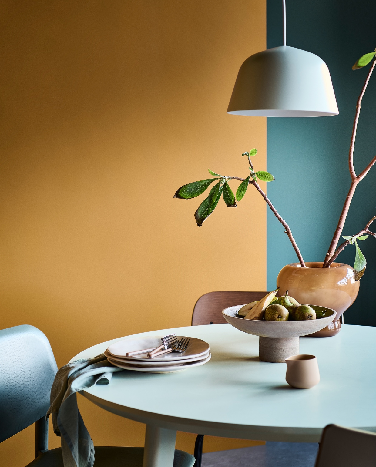 Muurverf links Desert, rechts Purple Blue van vtwonen, liter € 23,99, 2,5 liter € 39,99, lakverf tafel Ice, 1 liter € 41,99. M.m.v. vtwonen.be (houten eetkamerstoel van Menu, petrolkleurige stoel van Hay, beige eetkamerstoel van Kartell), ikea (eettafel), hm.com (glazen vaas, houten etagère, linnen servet), zarahome.com (aardewerken borden, bestek), dumu (porseleinen melkkan).