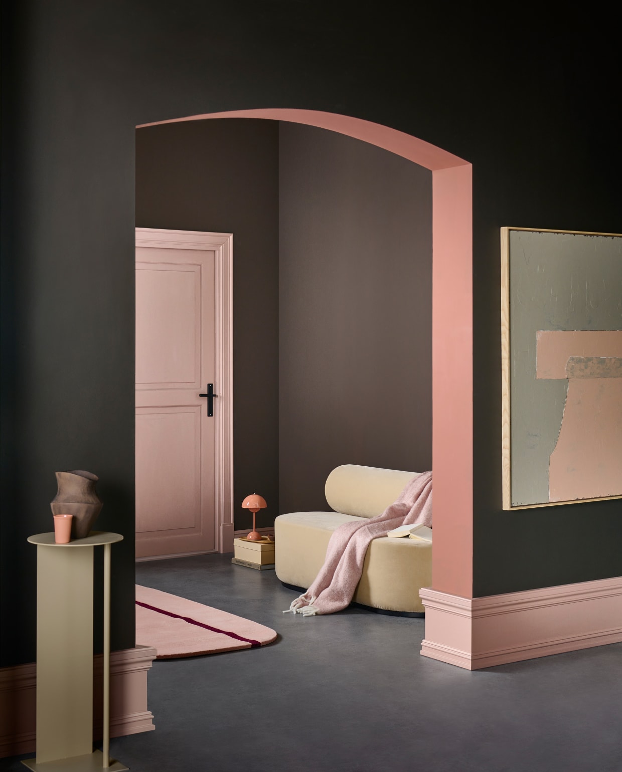 Muurverf deur en plinten Soft Clay, binnenkant boog Blusher, voorste wand Soil, achterwand bij deur en rechtermuur Warm Brown van vtwonen, liter € 23,99, 2,5 liter € 39,99.M.m.v. festamsterdam.nl (bank), hkliving.com (schilderij), vtwonen.be (vloerkleed van Normann Copenhagen, pilaar van Ferm Living), andtradition.com (tafellamp), zarahome.com (vaas, houten dienblad), dumu.nl (mok), hm.com (plaid). Overig privébezit.