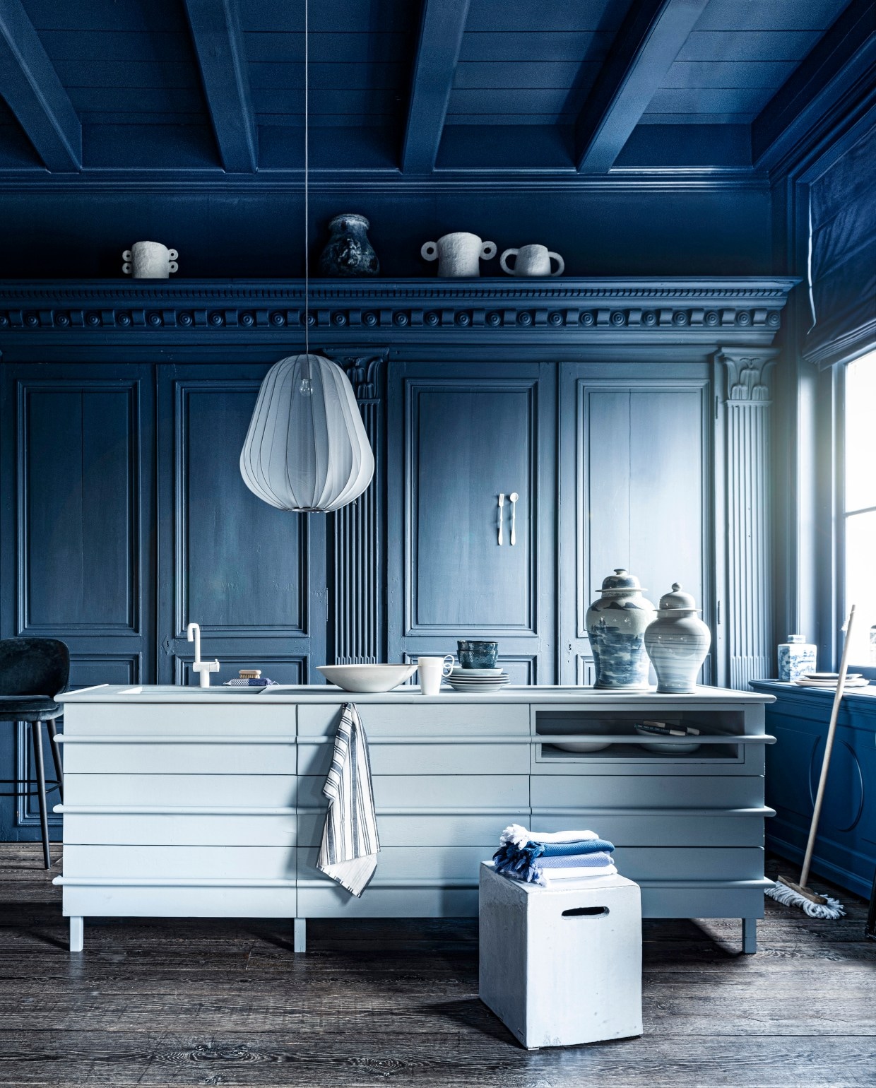 Blauw-witte potten, per stuk € 149,95, vierkante pot € 44,95, bezem € 13,95 (loods5). Witte pot van Serax bovenin links € 54,-, witte pot bovenin midden € 54,-, kraan prijs op aanvraag, witte schaal, prijs op aanvraag, vierkante kruk € 2241,- (badenbaden.nl). Donkere grote vaas boven op plank, set van 4 € 1936,-, 18e-eeuwse houten vloer, per m² € 168,19 (pietjonker). Gordijnstof 295 breed, per meter € 103,- (wva). Keukeneiland prijs op aanvraag (com-anders). Vork en lepel € 40,- (lisannevanzanten). Hamamdoeken vanaf € 9,60 (ottomania.nl). Gestreepte theedoeken, set van 3 € 9,99 (hm.com). Barkruk € 2174,- (covanderhorst). Zeep € 22,50, zeepborstel € 11,50, notitieboeken per stuk € 19,95 (maisonnl.com). Witte mok € 8,95, blauw-wit bord € 13,95 (hkliving.nl). Houten dienblad Zanat € 113,- (homestede). In het midden bord van Leonardo, Ø 23 cm € 9,95, blauwe kom van Leonardo, Ø 15 cm € 9,95, Balloon hanglamp van Bolia € 469,- (vtwonen.be). Overig privébezit.