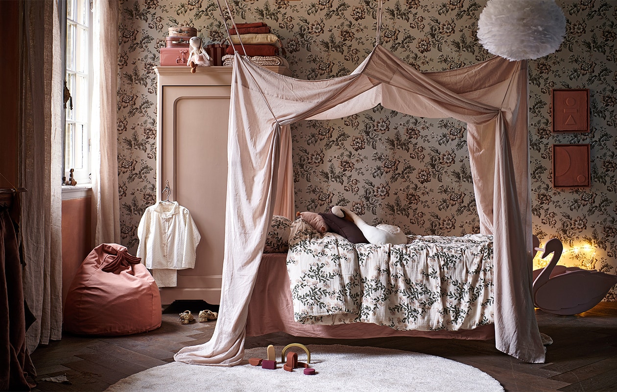 Behang Rosenholm Wheat van Sandberg € 111,56 (sandbergwallpaper.com). Wit spijlenbed € 135,- (burbri.nl). Oude houten kast € 125,- (vandijkenko.nl). Juten vloerkleed Dots van Ferm Living € 39,- (vtwonen.nl). Dekbedovertrek Honeysuckle Muslin van Garbo &amp; Friends, 140×200 cm € 90,- (lidor.nl). Kussen in vorm van huis Celia Mink van Camomile London € 39,95, gevlochten opbergmand appelvorm van Ferm Living € 45,-, miniatuur-items van Maileg: roze, houten bed € 35,-, keuken € 70,-, badkamerwastafel € 32,50, ballet dance room met big sister mouse € 57,50 (storeofdaydreams.com). Mini-schommel € 9,95 (feloufamilyhouses.nl). Roze ronde poppenhuistafel € 12,95 (maileg.com). Zwart poppenhuis € 12,95 (ilovespeelgoed.nl). Knuffel konijn € 22,99, houten poppenhuismeubels bed, kast en stoel € 19,99 (zarahome.com). Wanddecoratie ballon Byon Dusty small € 29,95 (psikhouvanjou.nl). Stof voor gordijnen roze gewassen linnen € 39,95 (kniphal.nl). Vloer visgraat eiken bruin geolied uit de vtwonen collectie € 69,95/m2 (karwei.nl).