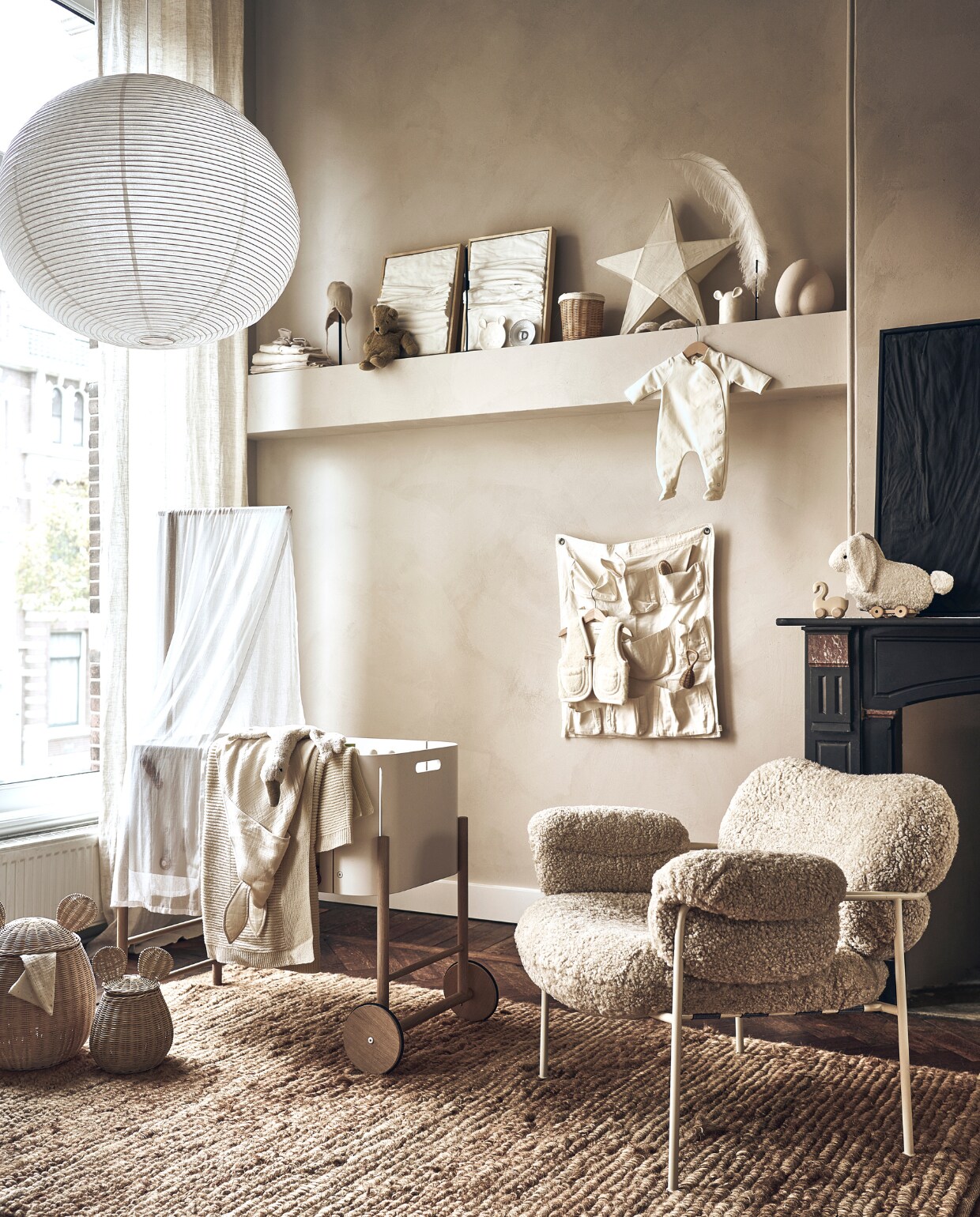 Grote lamp van Hay € 739,- (loods5.nl). Babybed € 629,-, beige deken € 90,-, pittenzak gans € 75,-, handdoek konijn € 59,-, lakens per stuk vanaf € 29,50, beige sloffen € 36,-, beige mutsje € 36,-, knuffelbeer € 35,-, Anouk Kramer bord met letter D extra small € 40,-, witte sterlamp € 69,-, babysloffen met schapenvacht € 69,-, wit babypakje € 52,-, houten zwaan € 30,-, wit konijn met touwtje € 42,-, witte vakkenzak € 59,-, witte bodywarmer € 67,-, konijnenbijtring € 16,- (thearchivestore.com). Rieten mand op plank € 17,99, rieten manden met oor, groot € 49,99 en klein € 39,99, wit bord met oren € 11,99, wit bakje met oren € 15,99, rieten rammelaar € 15,99, kam € 15,99 (zarahome.com). Witte kunst drieluik Triptych Water &amp; Air, 30×40 cm € 1100,-, zwart kunstwerk Water &amp; Cracked Mud, 60×80 cm € 990,- (studio-harte.com). Veer op staander € 37,50 (taxidermy). Sierbol op plank € 44,95 (eijerkamp). Beige stoel met witte poten, prijs op aanvraag (homestede). Muurverf en vloer onbekend. Overig privébezit.