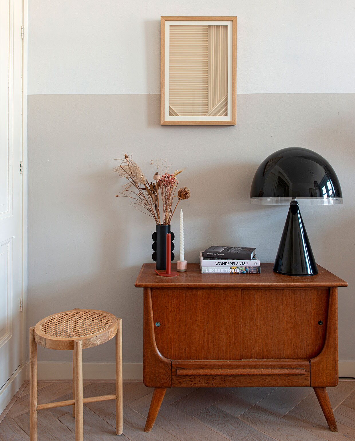 Schilderij en kruk HKliving, vintage mid-century kast Sprinkelhop, vintage designlamp Baobab van iGuzzini is een kringloopvondst, zwart vaasje H&amp;M Home. Overig onbekend.