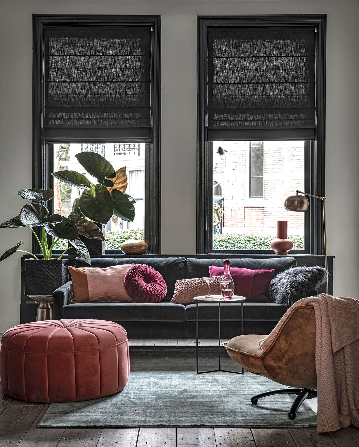 Driezitsbank Astha in Velours Dark Grey, grote poef Dixie in Velours Vintage Rosa (sofacompany.com). Fauteuil Dirk - (hetkabinet.nl). Grijsgroen vloerkleed,  okergele vaas  rond aubergine kleurig velours kussentje  oudroze smock kussentje oudroze plaid- (woondock.nl). Bijzettafel Corinthia van Lifestyle, metaal brons, ) , bijzettafel Copenhagen van Rivièra Maison  mat bronzen vloerlamp Nordal Globe, -, terra kleurige vaas Theseus van Urban Nature Culture (vtwonen.be). Roze glazen karaf , roze cocktailglazen (hm.com). Kussen met twee vlakken in okergeel/zachtroze, en donkerrood/donkerroze,  (kus-sen.nl). Grijs vachtkussentje Tibet Nightsquare (zenza.com).