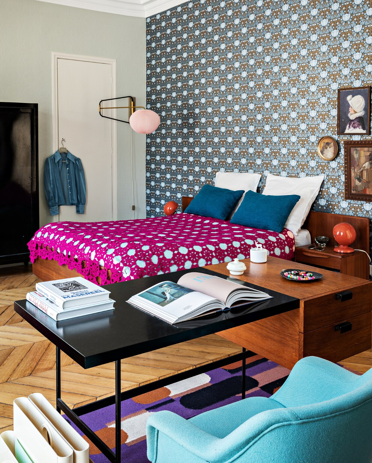 Behang Etoffe. Kast, bed, roze wandlamp, crochet-sprei, Pantone-bedlampen en Pierre Paulin-bureau vintage (o.a. via Selency.fr en vlooienmarkten). Vloerkleed Oman Élitis.