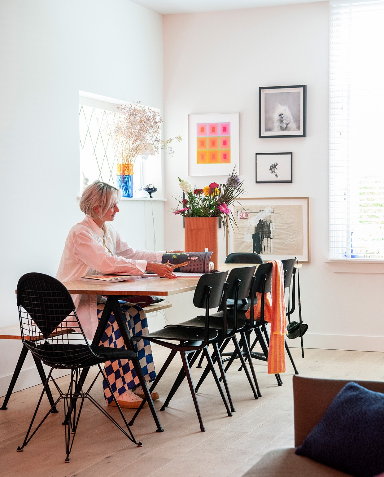 Tafel, bank en stoelen Ahrend voor Hay. Draadstoel Charles &amp; Ray Eames van DKR/Vitra. Grote vaas Muuto. Vaas blauw en oranje glasfabriek Beldi in Marrakesh. Vintage zeefdruk van Richard Anuszkiewicz. Werk Mika van Chris Berens. Klein zwart-wit werk van Daniel Berio. Pentekening in zwarte lijst van Kim David Bots. Landschap in houten lijst van Aldo van den Broek.