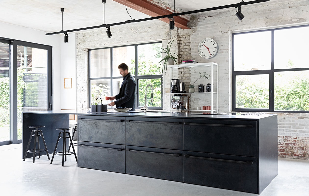 De keuken is een eigen ontwerp, binnenwerk op maat gemaakt door Marcel Hermans, beplating en werkblad van blauwstaal Schouren Metaal. Railarmatuur Venled. Toolbox Ferm Living. Krukken en open kast Ikea. Klok onbekend.