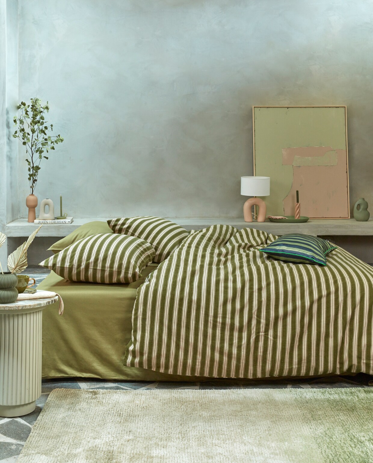 Katoenflanellen dekbedovertrek Pyjamas, 140×200/220 cm € 74,95, 200×200/220 cm € 139,95, 240×200/220 cm € 149,95 en 260×200/220 cm € 169,95, polyestersatijnen kussen met bies Pyjamas, 40×60 cm € 39,95.M.m.v. nordal.eu (marmeren bijzettafel Erie), hkliving.nl (schilderij), paviljoennoord.com (mok, bord). Overig privébezit.