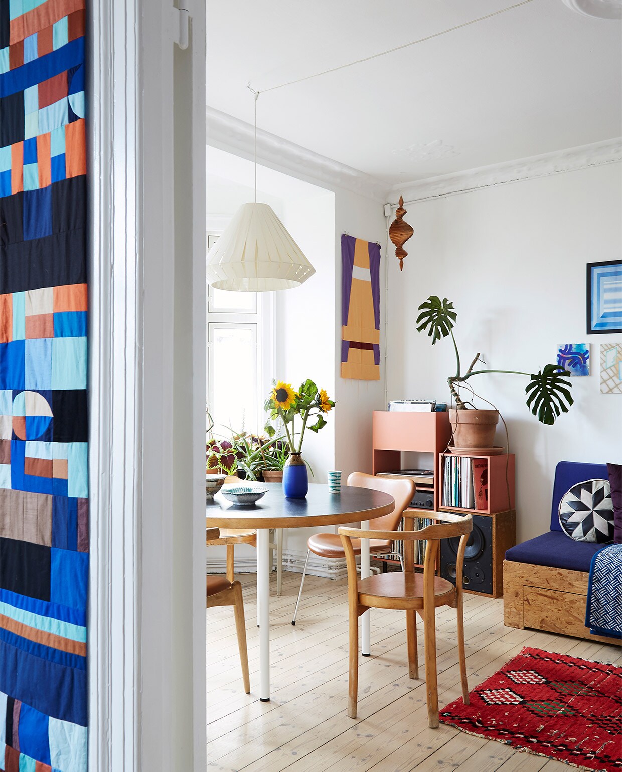 Tafel en designstoelen tweedehands. Hanglamp erfstuk. Gestapelde kastblokken en wandkleden zelfgemaakt. Vloerkleed uit Marokko. Kussen uit Istanboel.