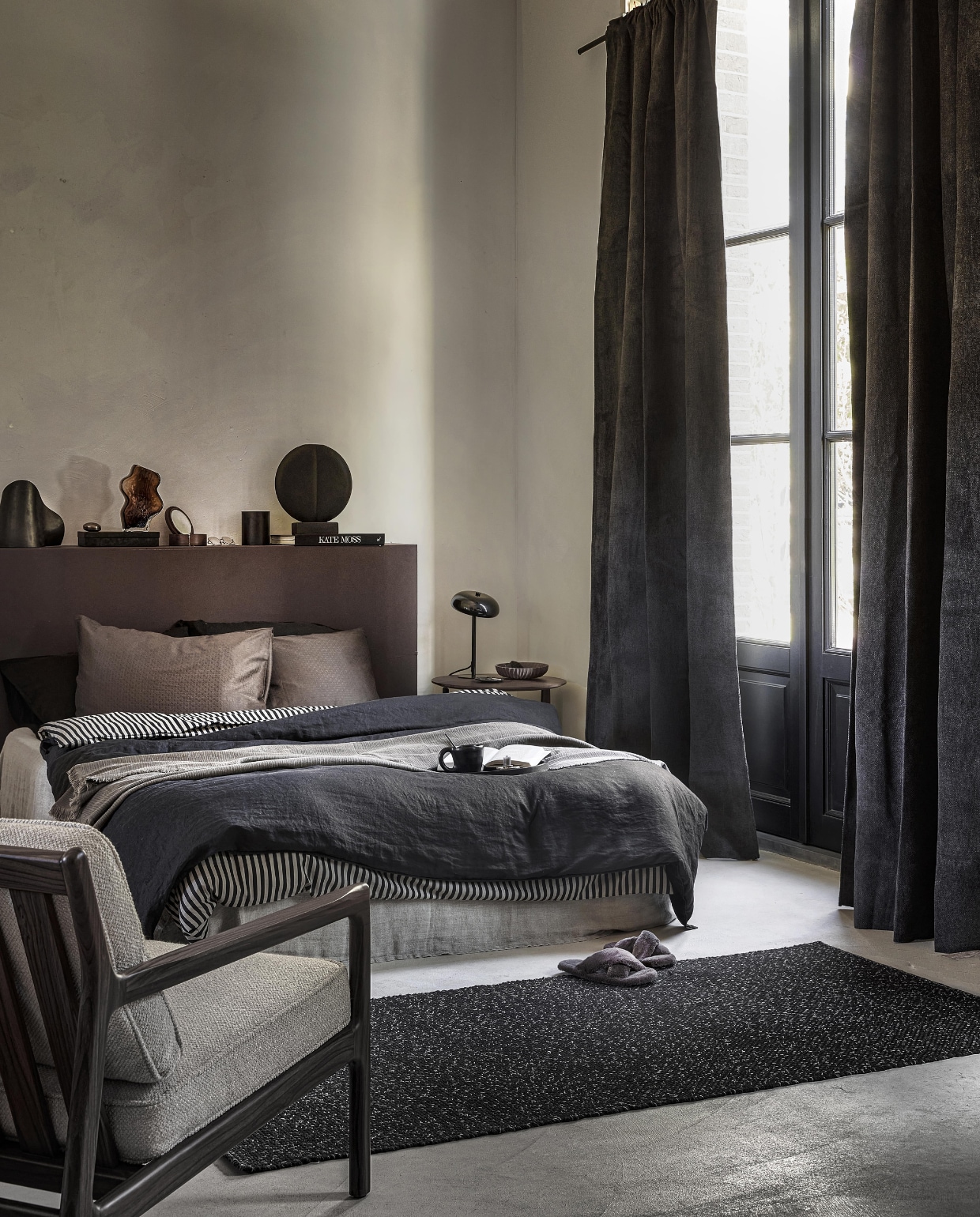 Uit de vtwonen collectie: Antraciet gordijn Snow, verduisterend, met plooi, 270×140 cm (hxb) € 64,99 M.m.v vanbinnen.com (fauteuil, bijzettafel), hm.com/home (linnen dekbedovertrek, dekbedovertrek met streep, organische bruine vaas, houten spiegel, bruine aardewerken schaal), zarahome.com (linnen onderlaken, pantoffels, metalen doos, geurkaars, zwarte tafellamp), homestede.nl (metalen organische tafellamp, rond sculptuur). Overig privébezit.