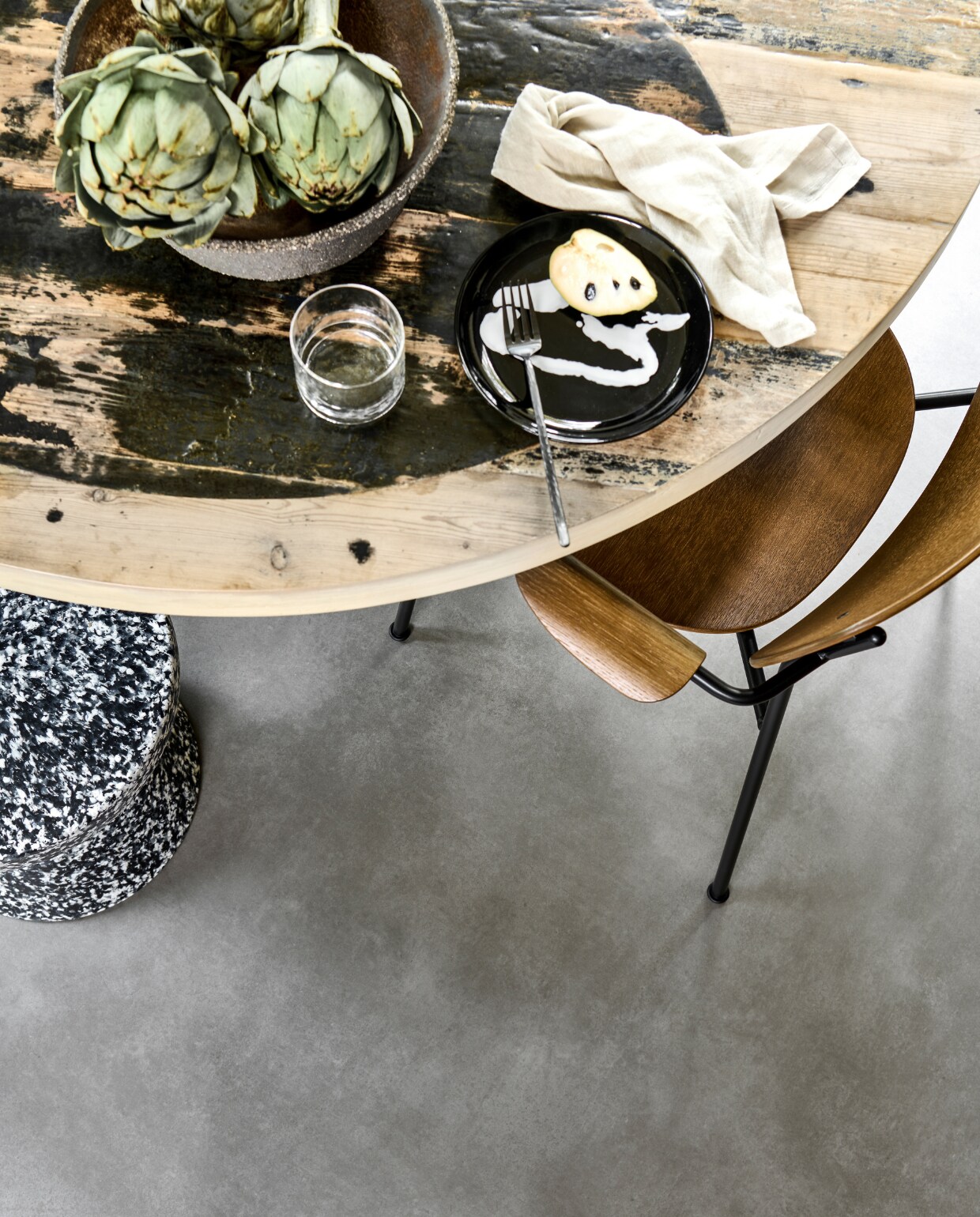 Novilon vloer Gruis, per m² € 35,65.M.m.v. vtwonen.nl (houten eetkamerstoel van Menu, gemêleerde kruk van Normann Copenhagen, bord van Serax), interiorcowboys.com (eettafel, aardewerken etagère), zarahome.com (glas, linnen servet, vork).